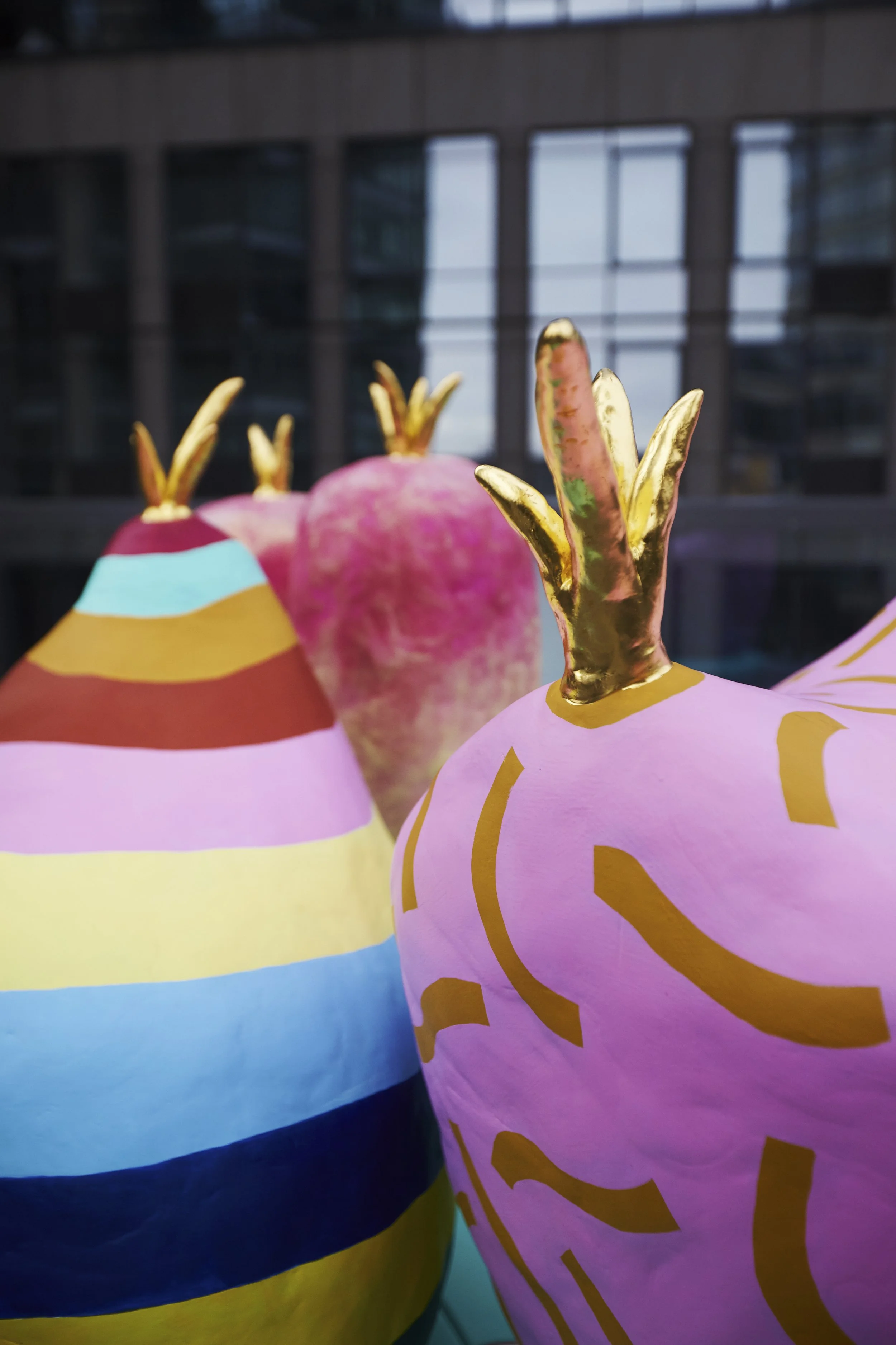 JGNA residential detail of colorful striped gourd sculptures against a city window