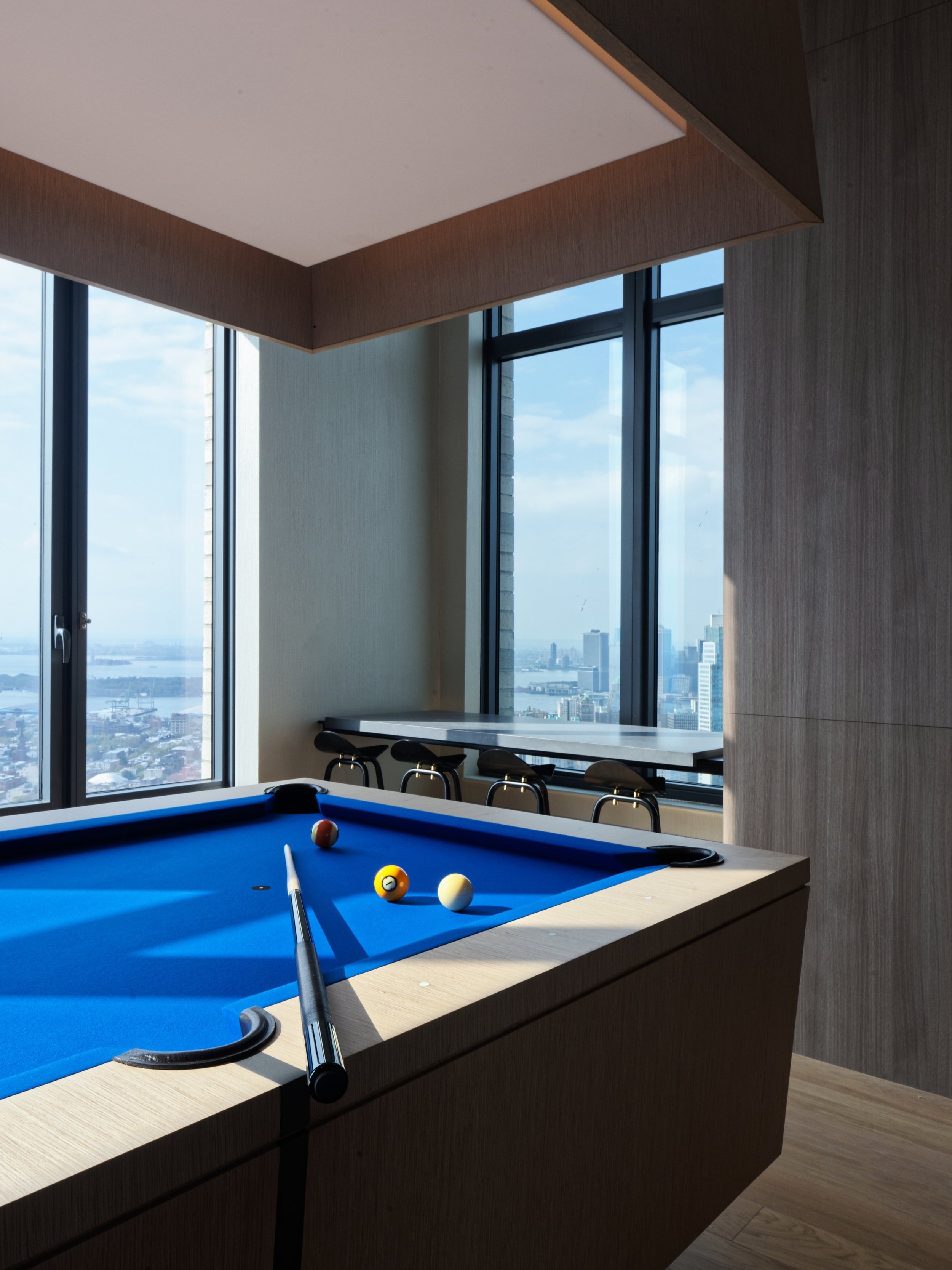 JGNA residential game room with a blue-felt pool table, window counter seating, and a water view