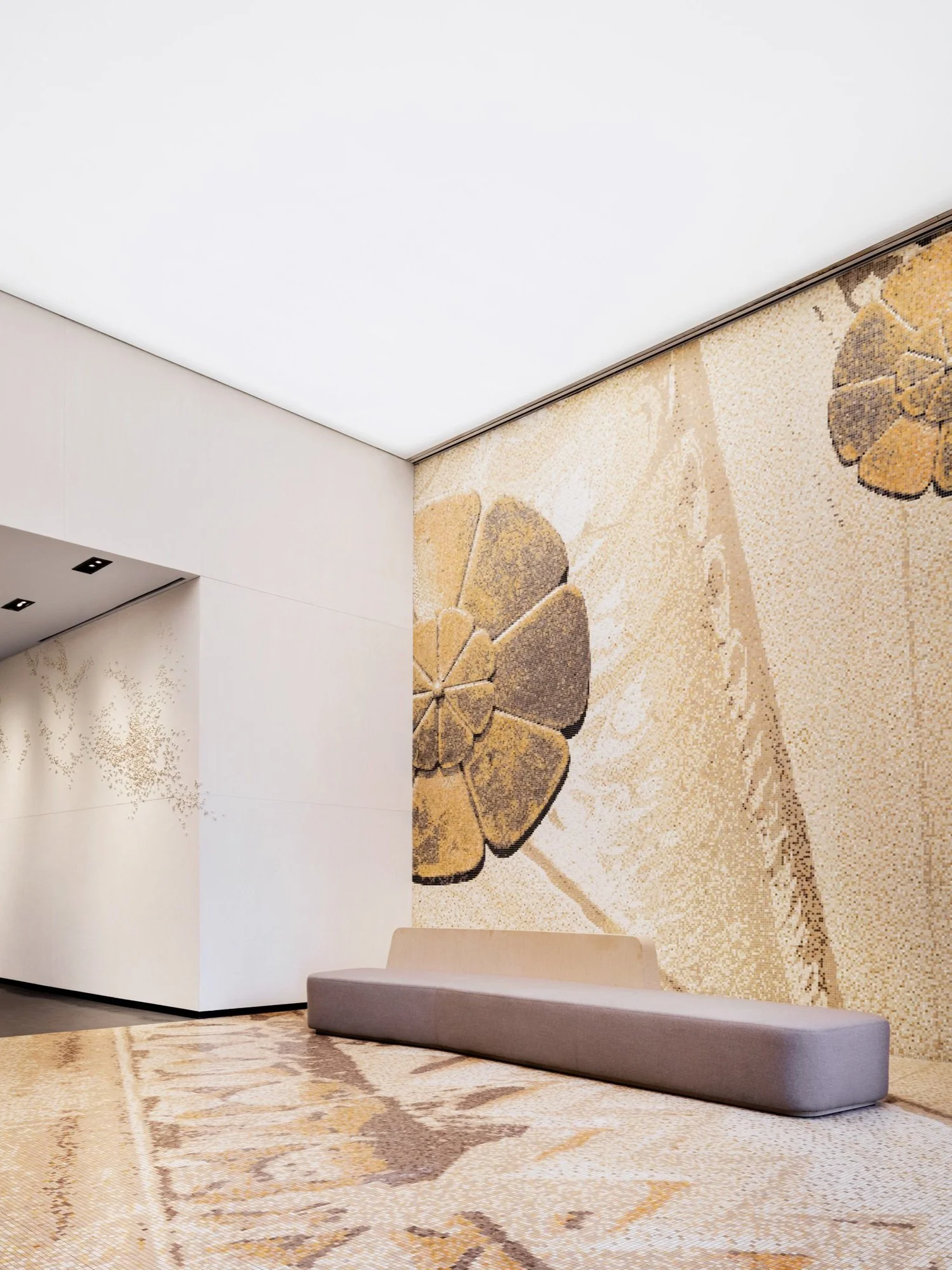 JGNA residential lobby with a wraparound botanical mosaic mural and a grey upholstered bench