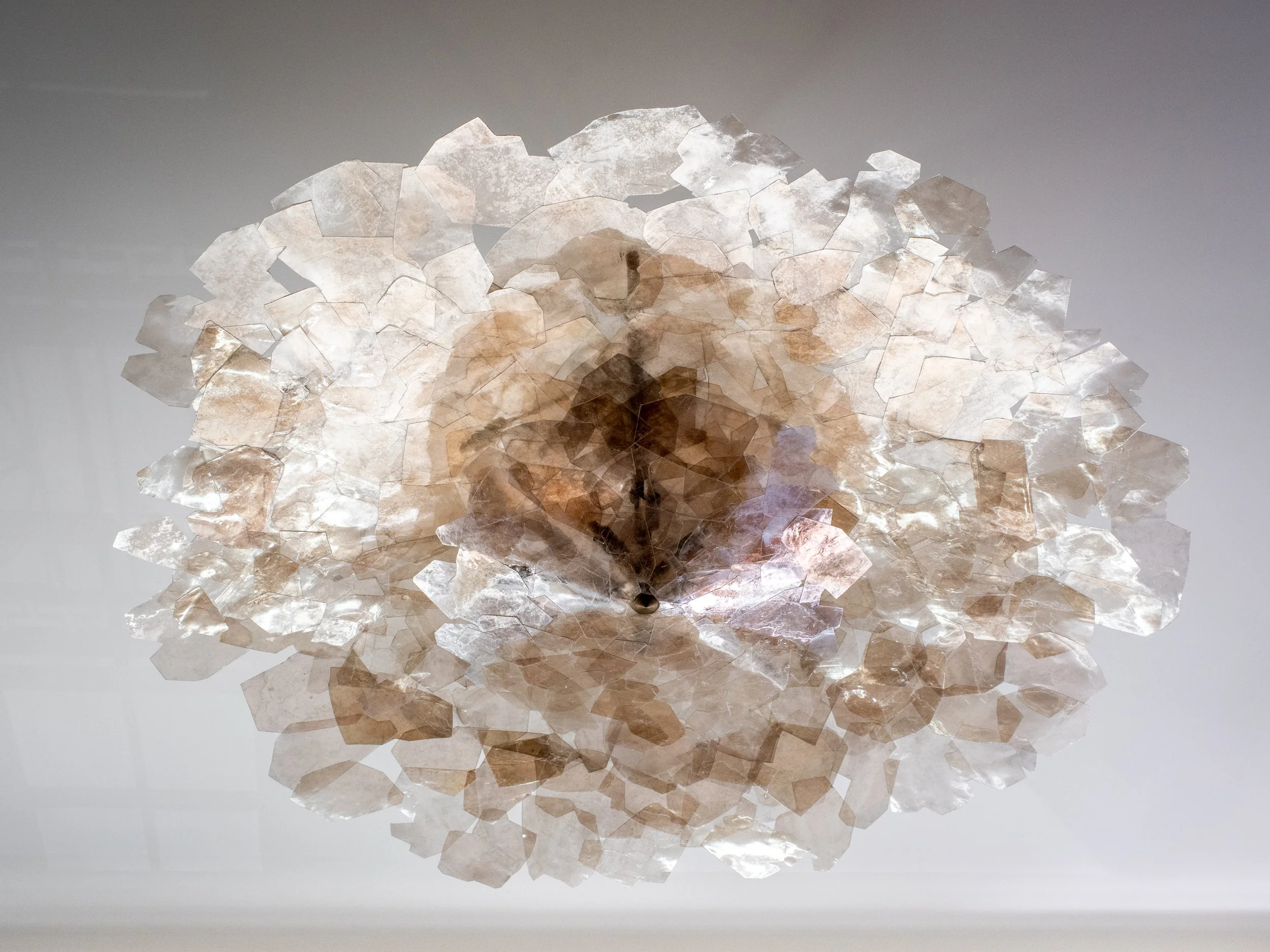 Close-up of a backlit selenite crystal cluster chandelier mounted on a white ceiling