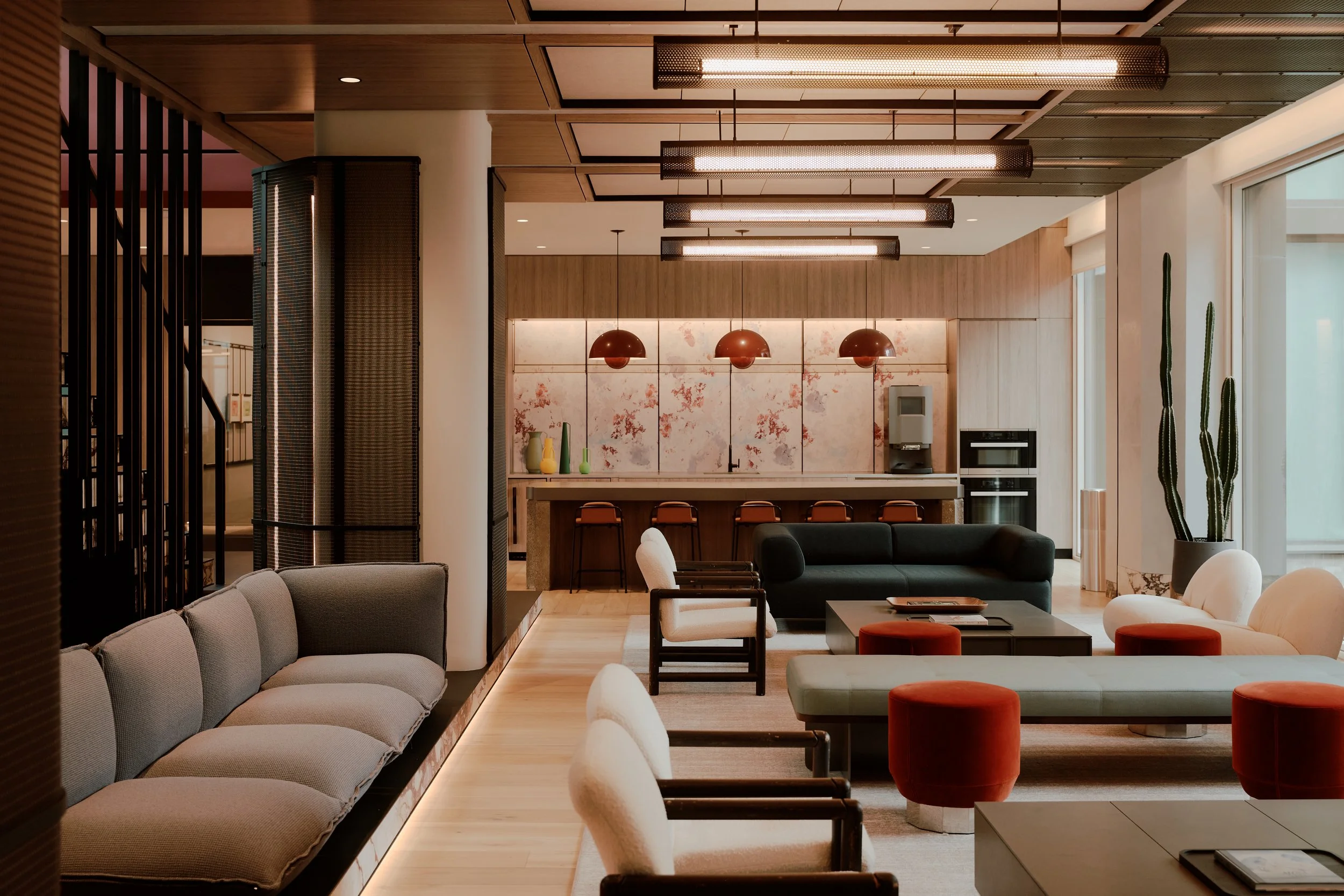 Residents lounge and entertaining kitchen with custom millwork, pendant lighting, and integrated seating at The Suffolk, a Lower East Side residential building, interiors by JG Neukomm Architecture