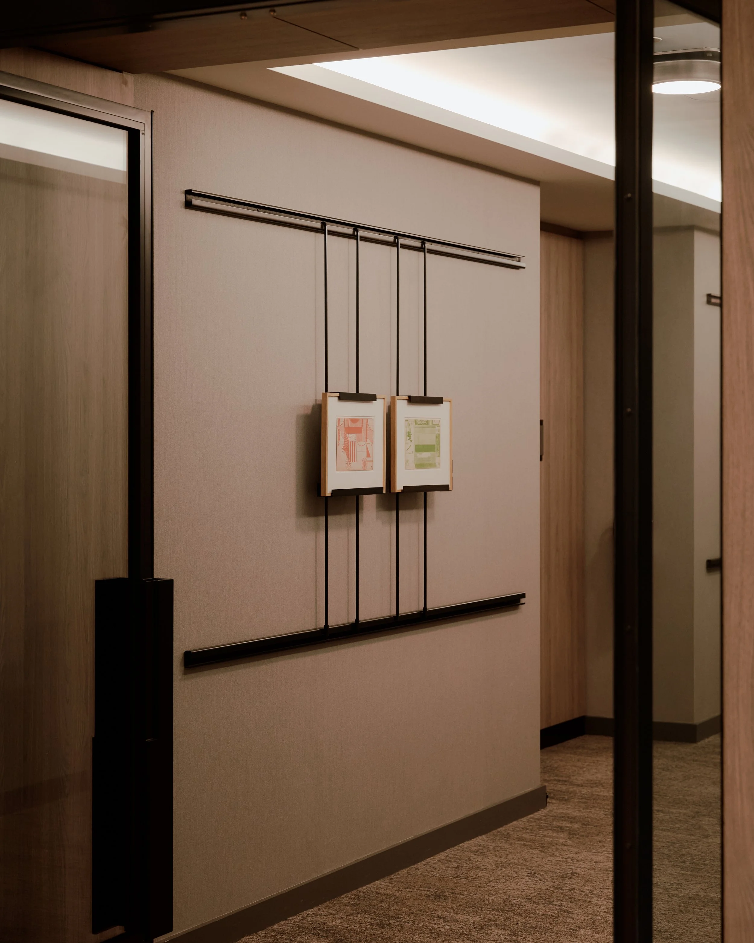 Elevator lobby with custom artwork display, warm wood finishes, and refined residential detailing at The Suffolk, a Lower East Side residential building, interiors by JG Neukomm Architecture