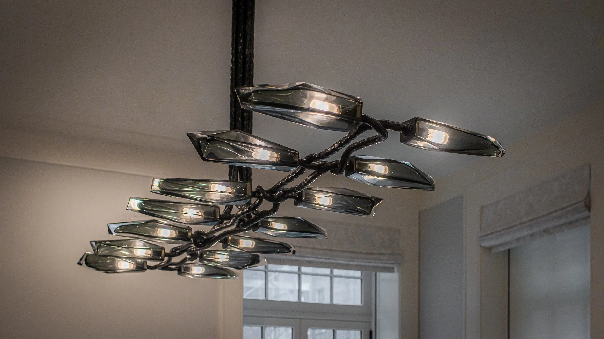Sculptural bronze chandelier with smoked-glass petal shades suspended near tall windows