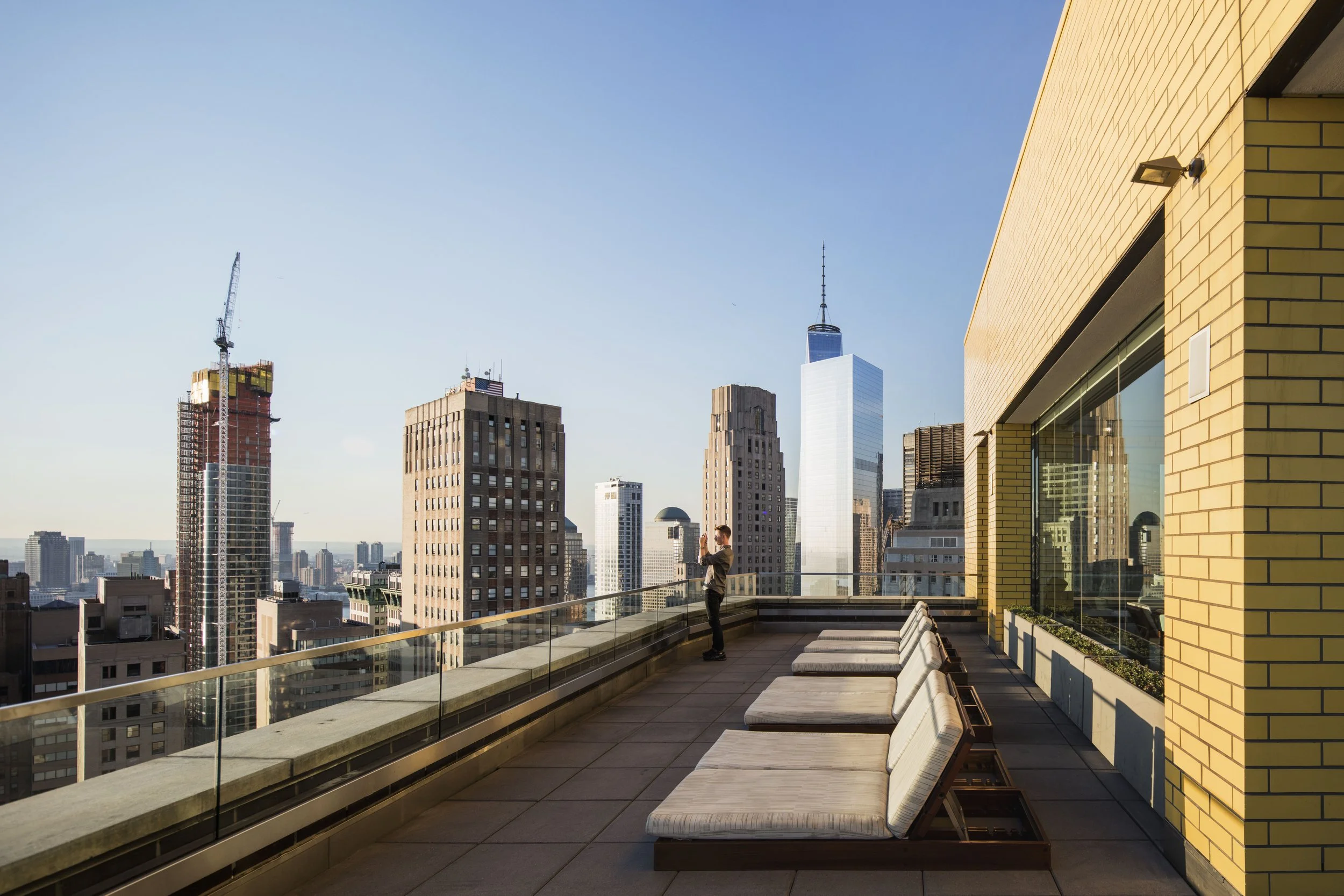 JGNA residential rooftop terrace with sun loungers overlooking the Lower Manhattan skyline