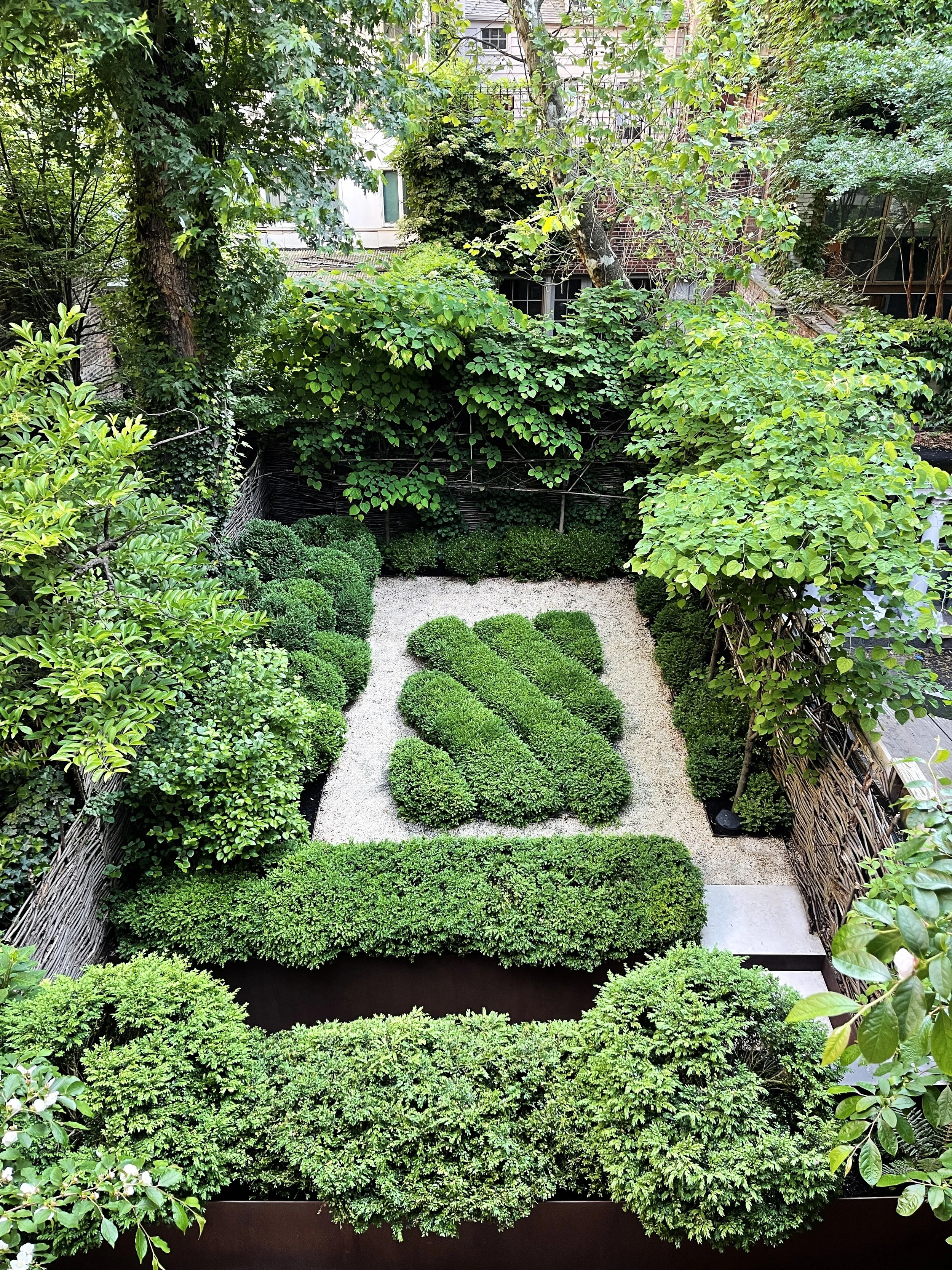 Lush private garden with manicured boxwood hedges, gravel paths, and mature trees at Fabien Baron Residence, West Village NYC by JG Neukomm Architecture