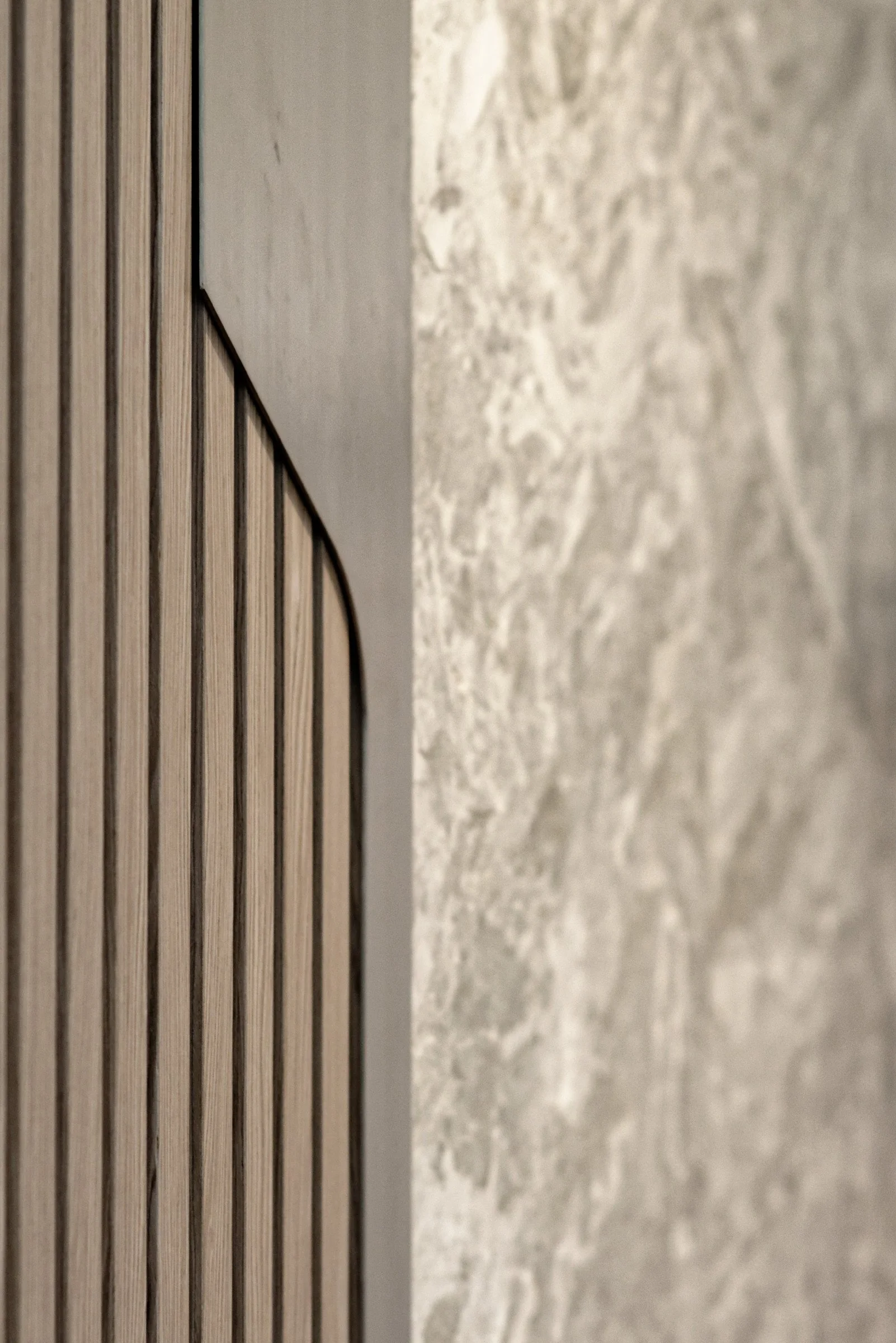JGNA residential lobby detail of ribbed oak paneling meeting a polished marble panel