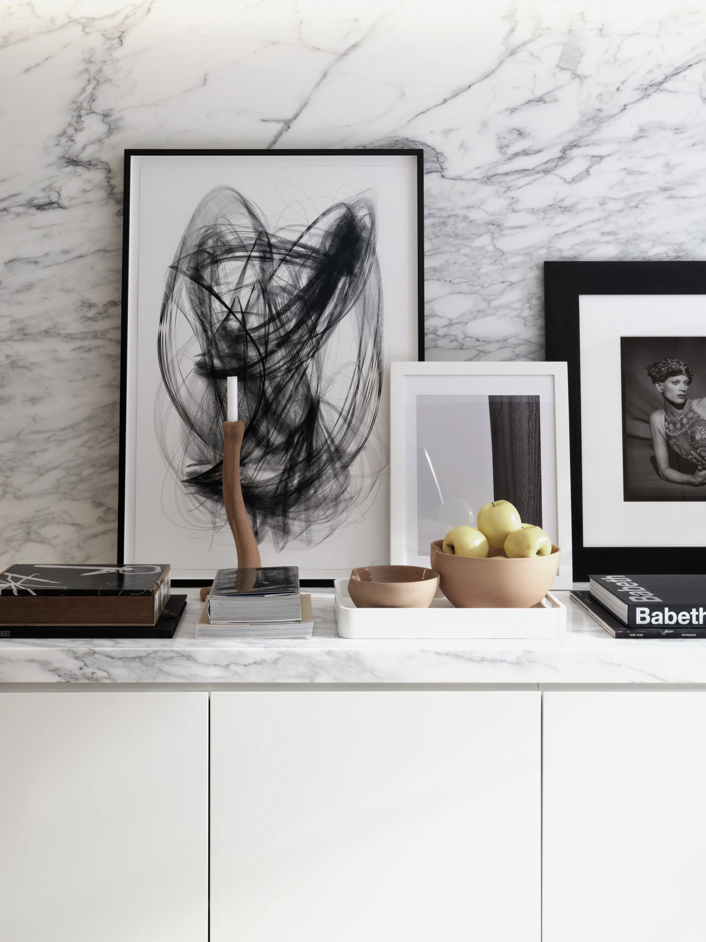 Carrara marble wall with abstract artwork, sculptural objects, and fashion prints in Fabien Baron Residence by JG Neukomm Architecture, West Village New York