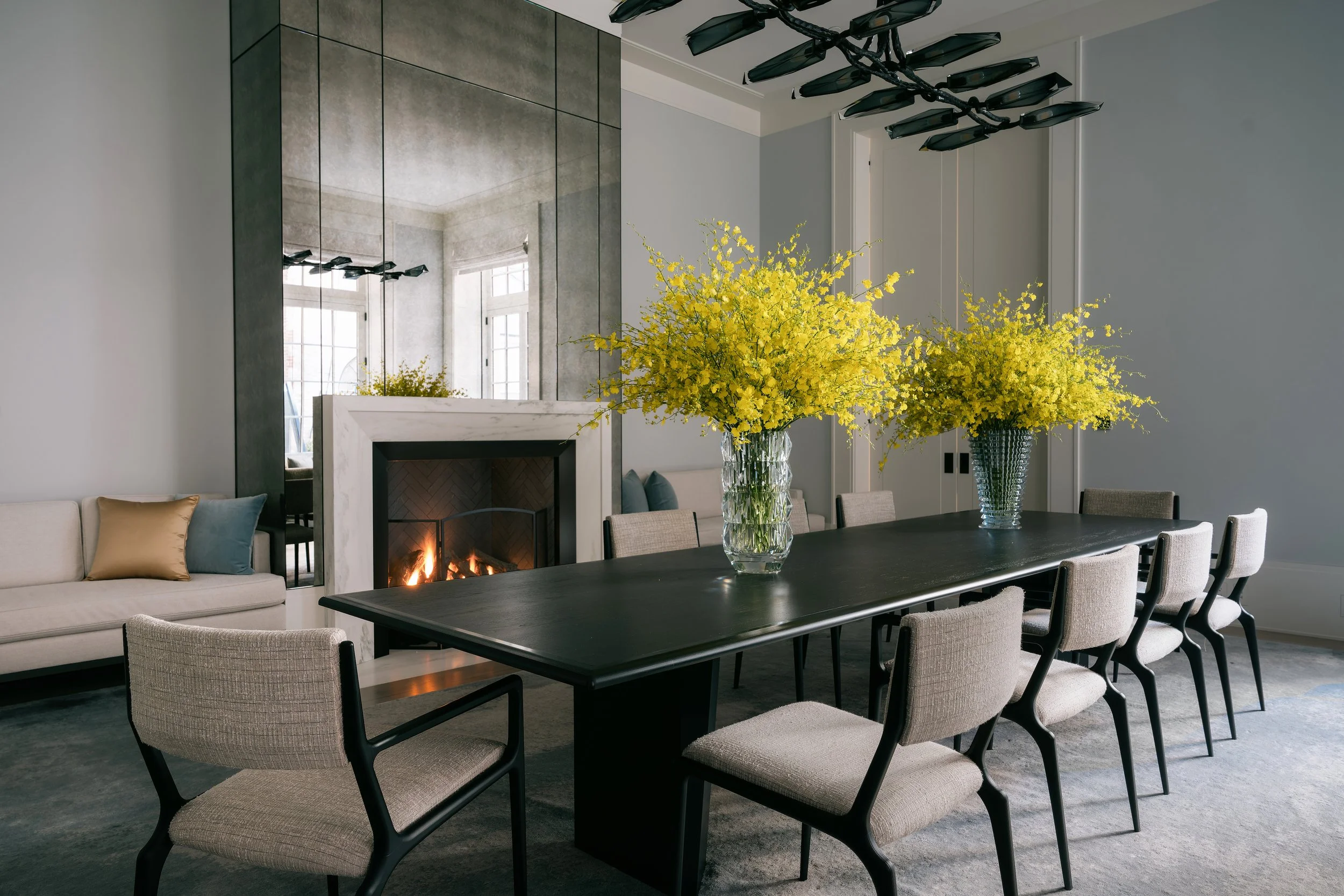 branch-chandelier.jpgDining room with a dark wood table, sculptural branch chandelier, mirrored wall, and marble fireplace