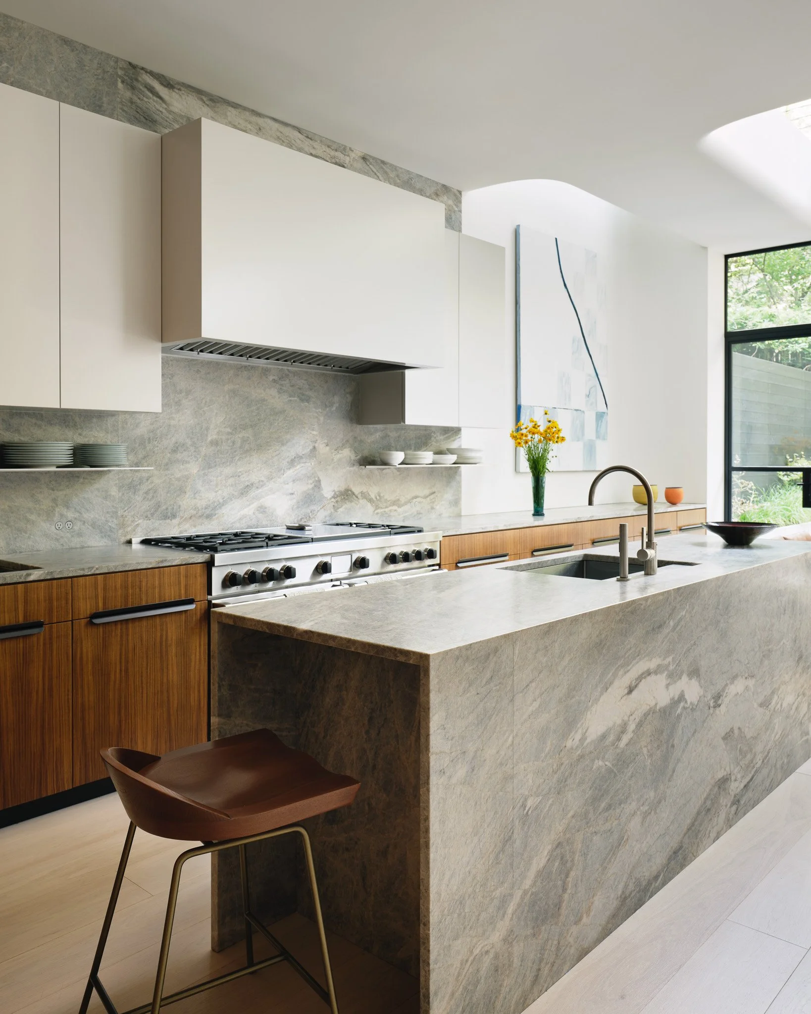 Kitchen with a veined marble waterfall island and custom wood cabinetry in a West Village townhouse by JG Neukomm Architecture