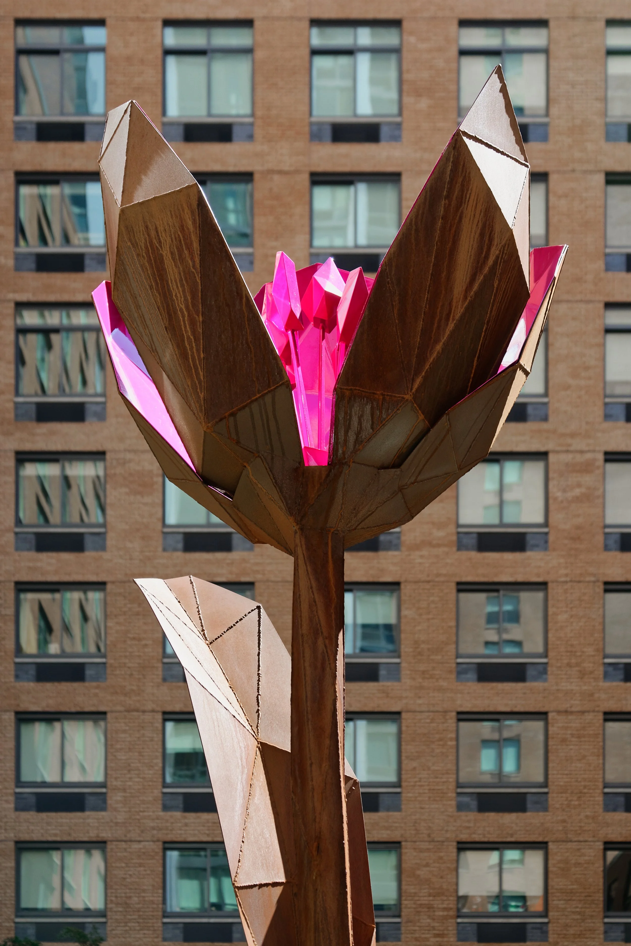 JGNA residential courtyard with a faceted wood and pink crystal flower sculpture against a brick tower