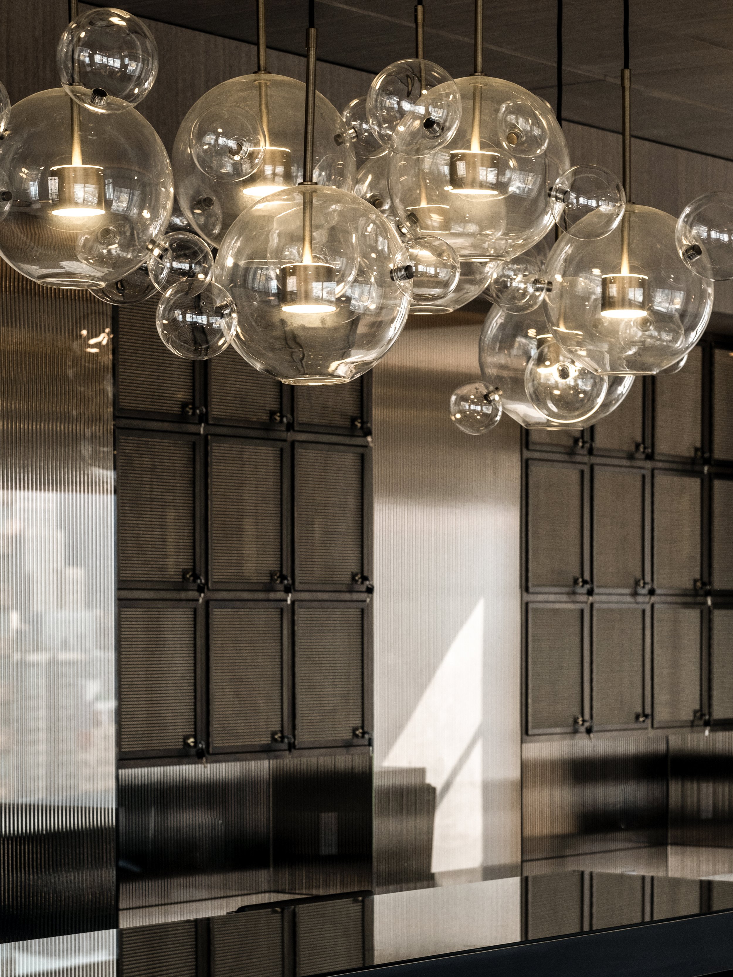 JGNA residential kitchen detail of a clustered bubble glass chandelier against gridded cabinetry