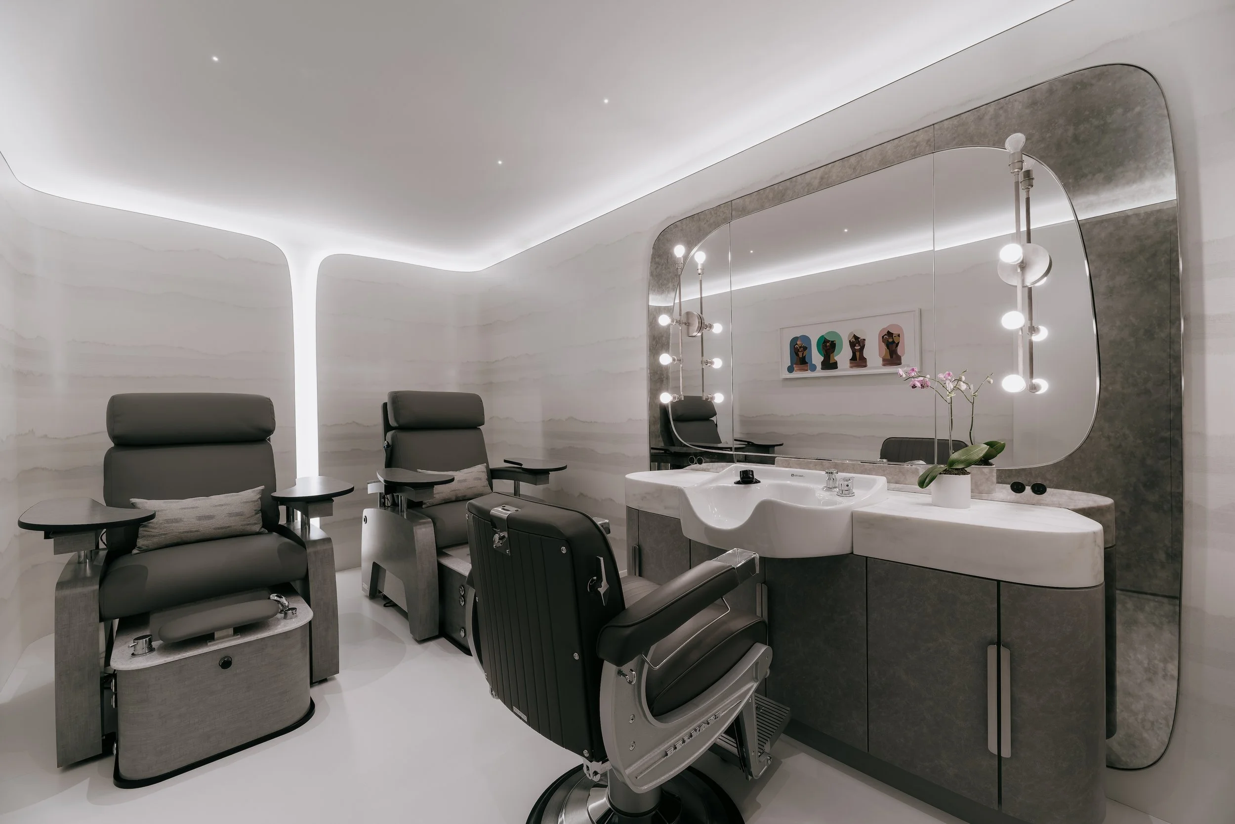 Private in-home salon with leather grooming chairs, a curved-edge mirror, and softly curved walls