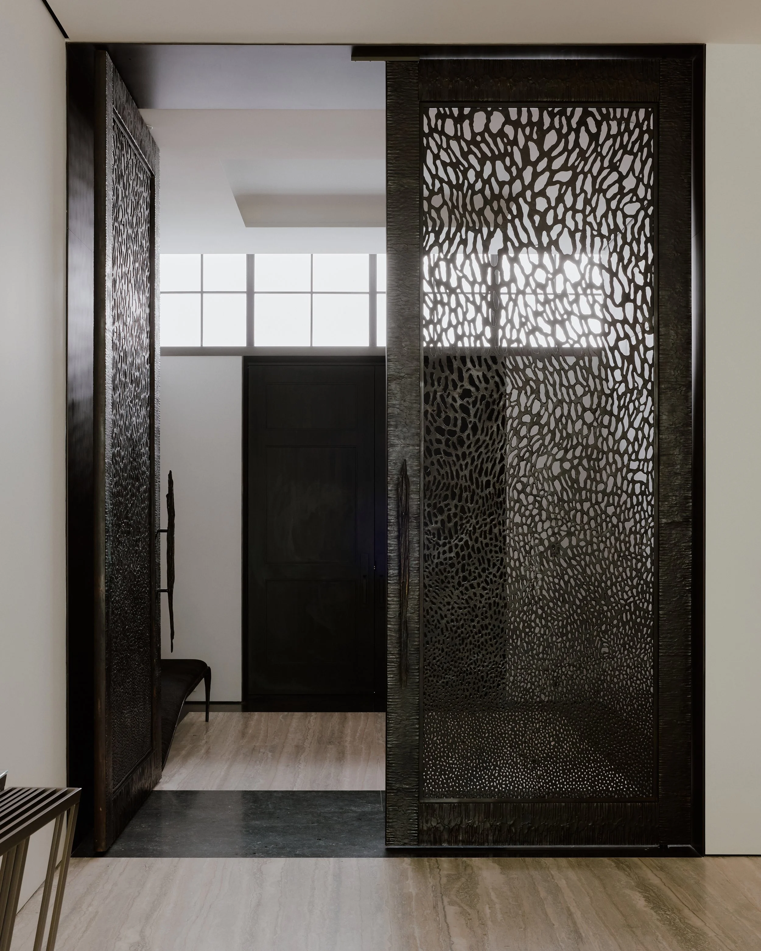 Entry foyer with a custom perforated-metal screen and travertine floor in a West Village townhouse by JG Neukomm Architecture