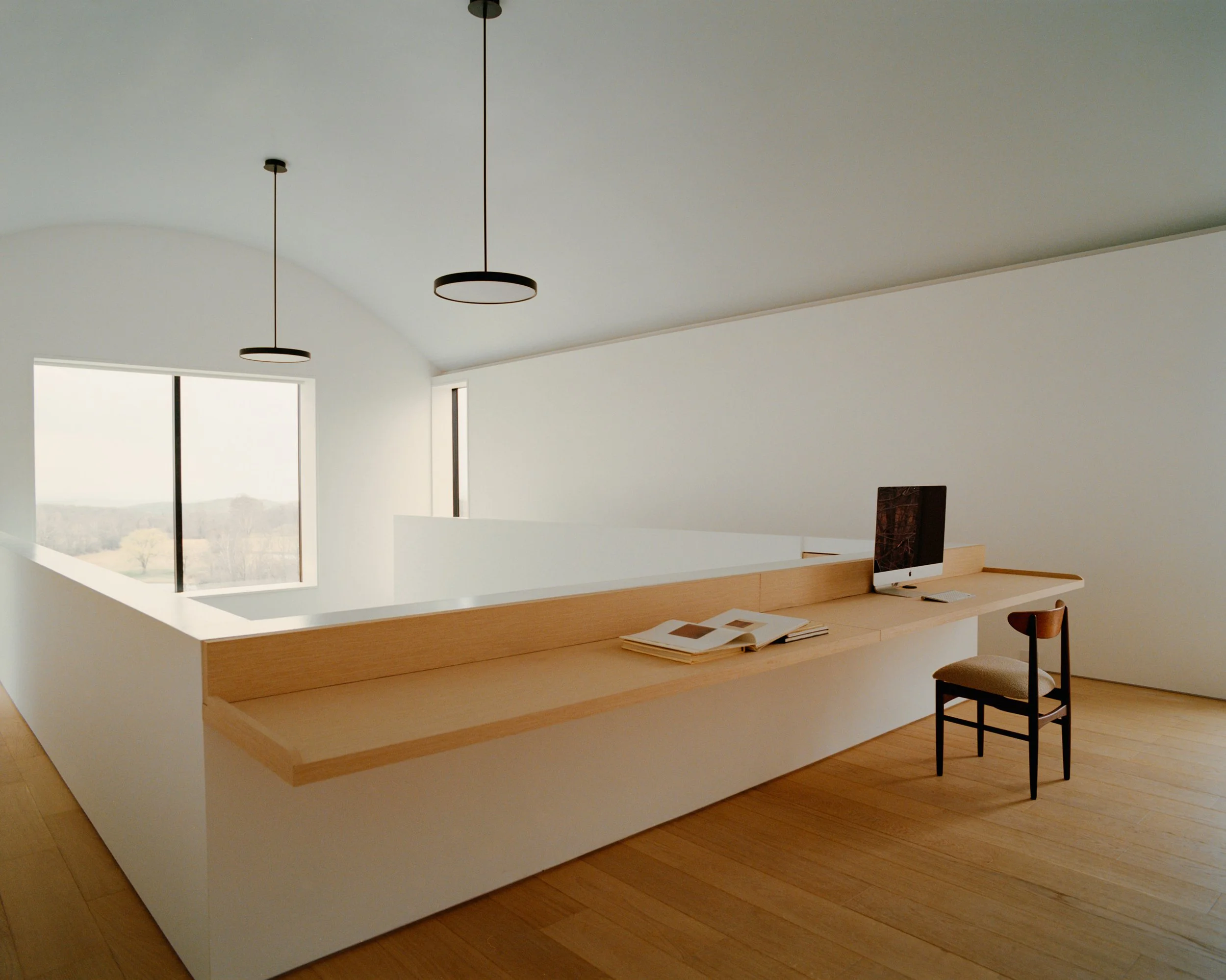 Mezzanine home office with a built-in wood desk under a barrel-vaulted ceiling at a Ghent, NY home by JG Neukomm Architecture