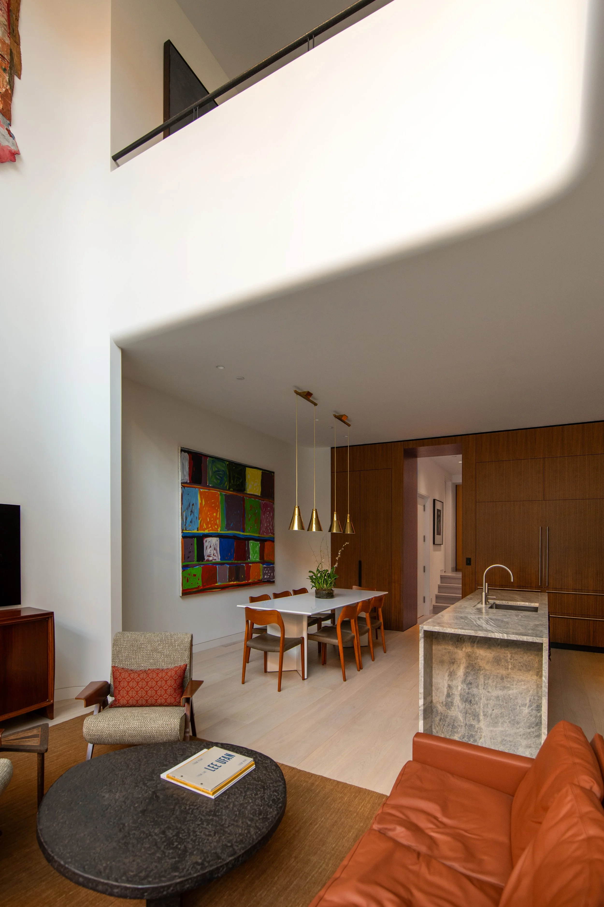 Open-plan living, dining, and kitchen with a marble island in a West Village townhouse by JG Neukomm Architecture