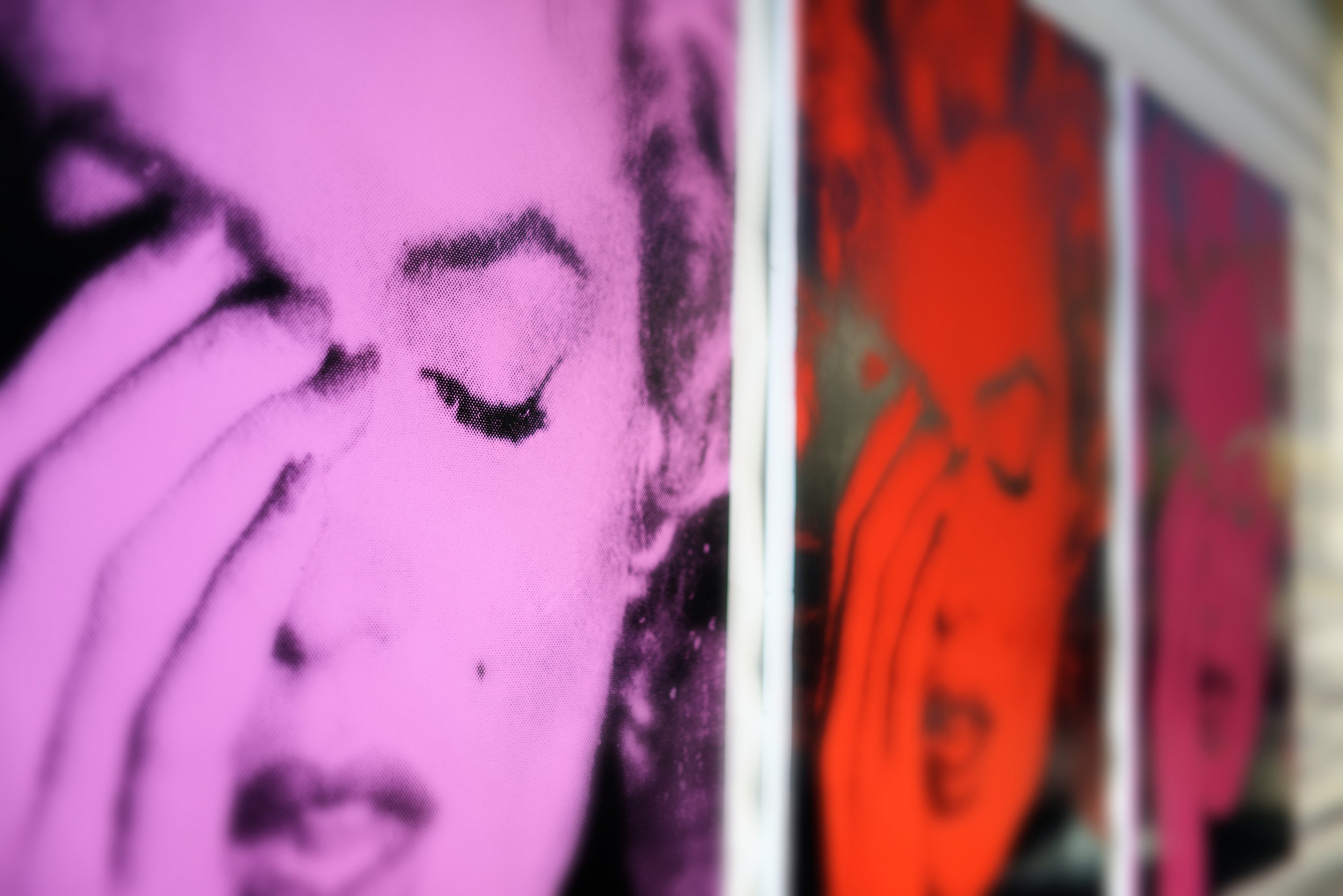 JGNA lounge detail of framed pop-art silkscreen portraits in pink, red, and magenta