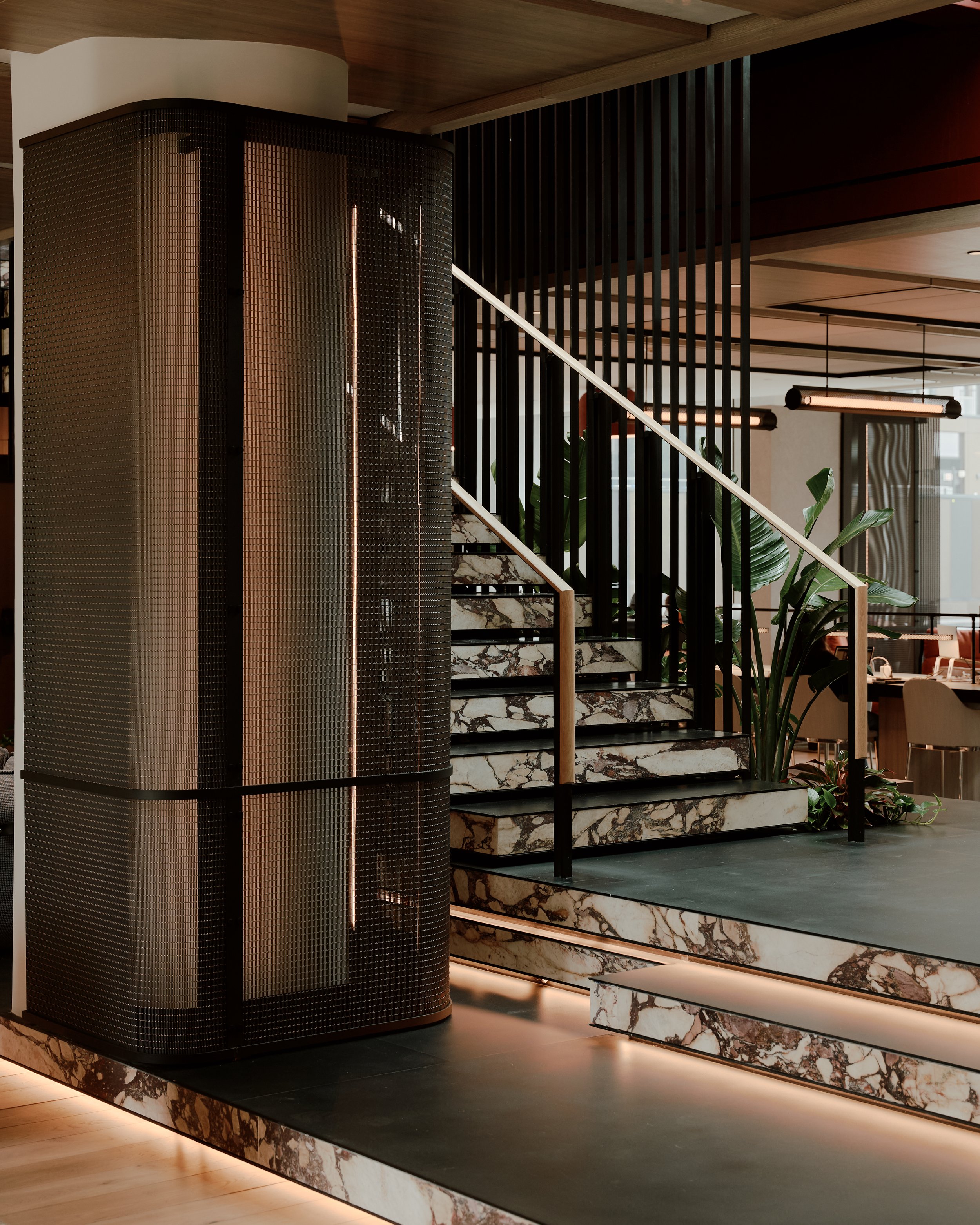 Lounge stair and column detail featuring marble-clad steps, sculptural metal screening, and integrated lighting at The Suffolk, a Lower East Side residential building, interiors by JG Neukomm Architecture