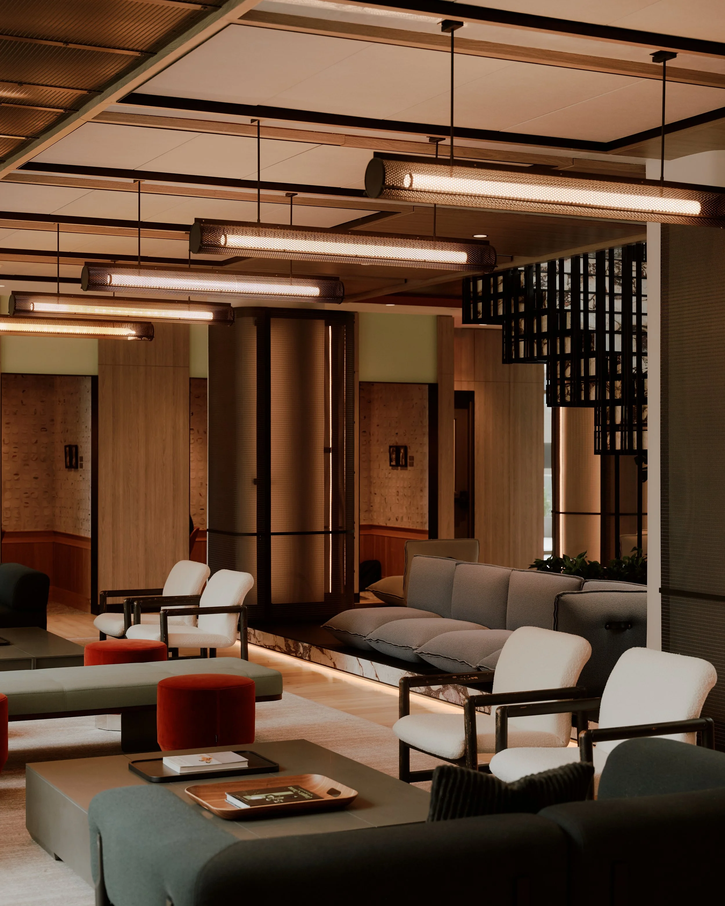Lounge seating area with custom furnishings, illuminated architectural details, and sculptural metal-clad columns at The Suffolk, a Lower East Side residential building, interiors by JG Neukomm Architecture
