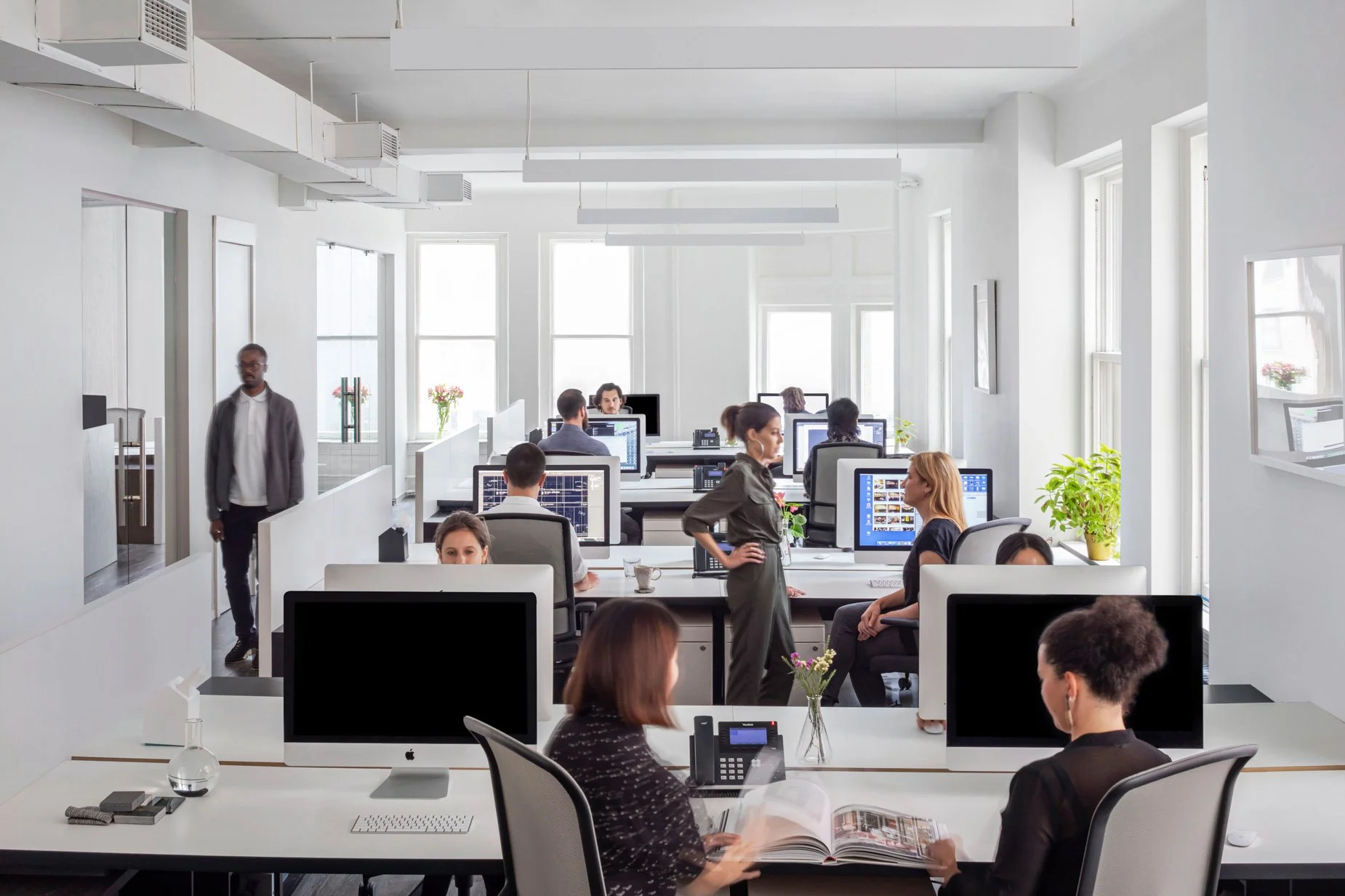 JGNA open-plan studio with team members at workstations beneath linear lighting and tall windows