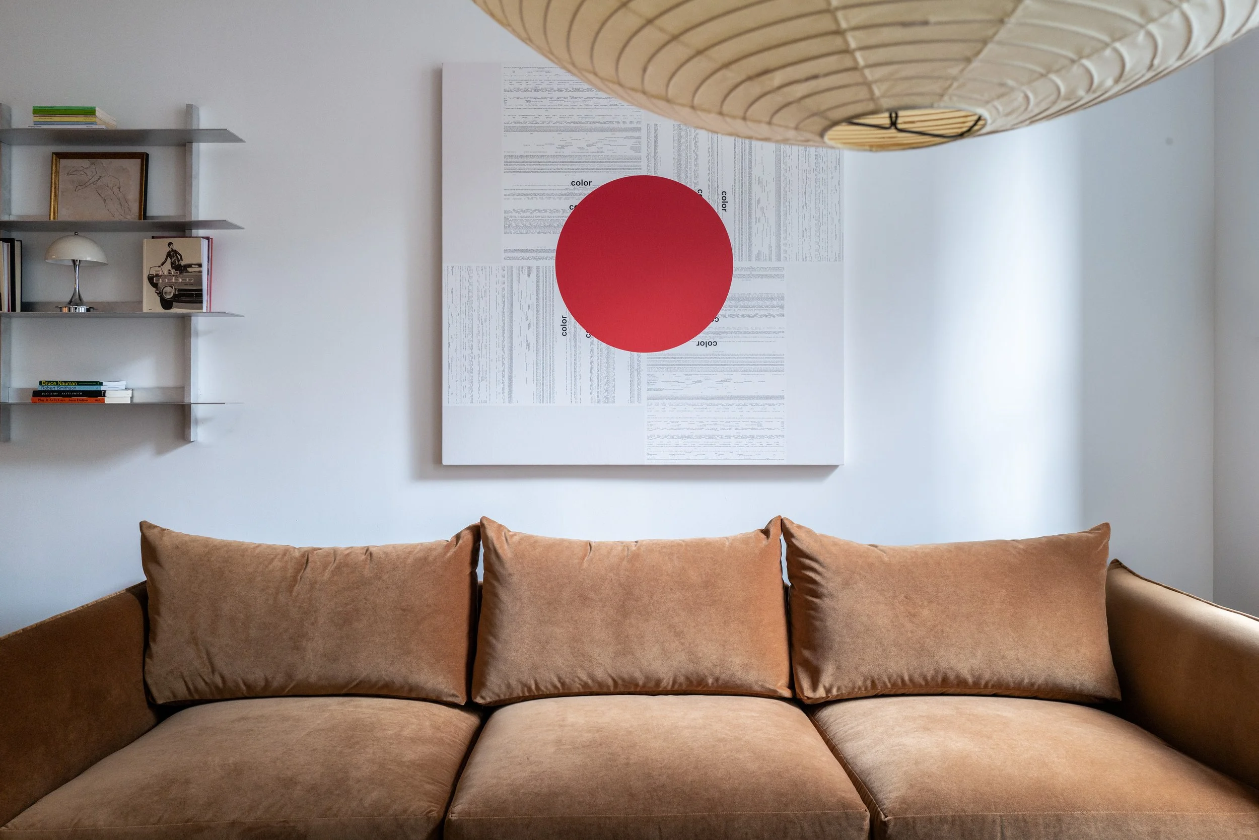 Living room sofa elevation beneath large-scale red circle canvas art and a paper globe pendant