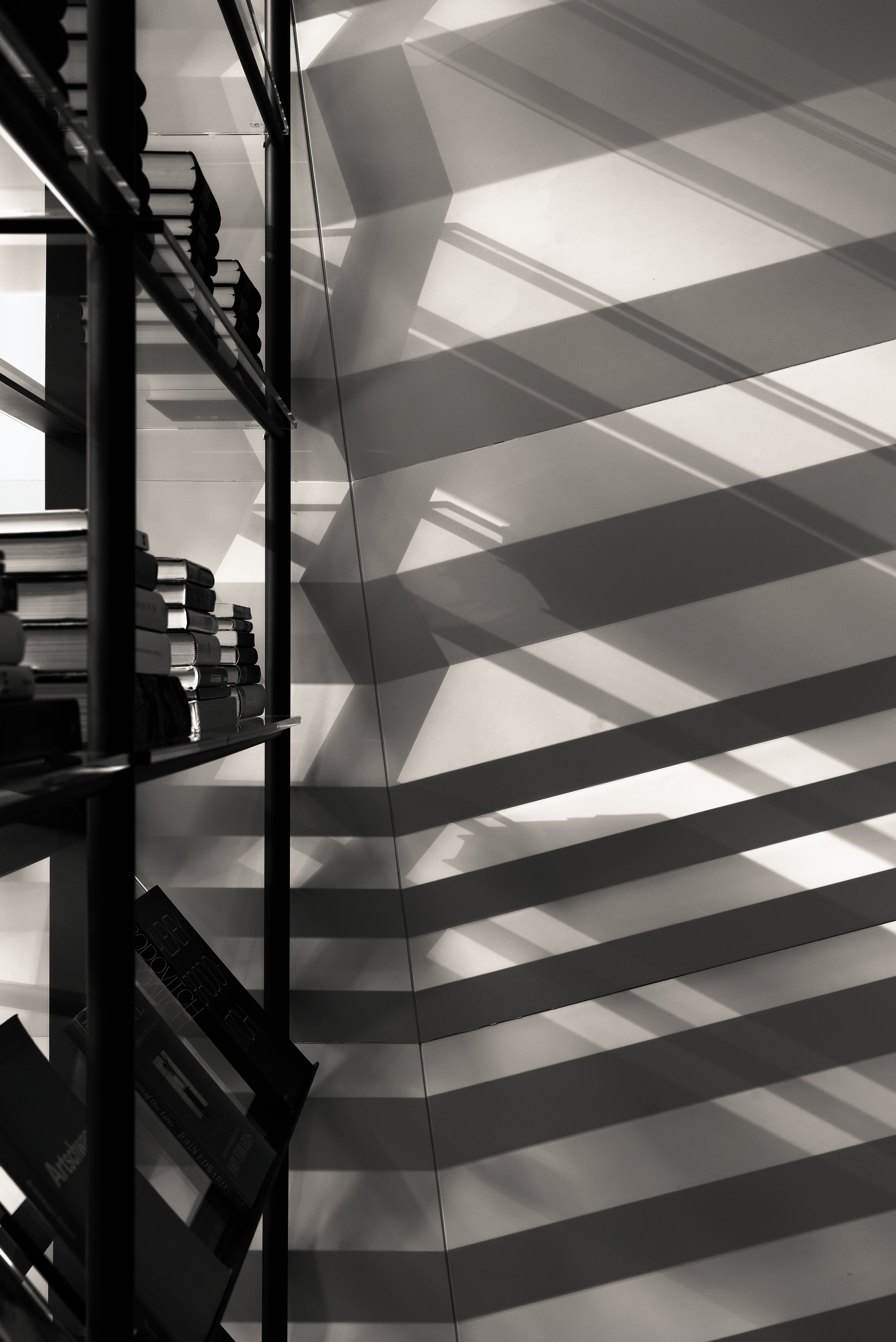 JGNA library detail of steel shelving with angular light and shadow across a wall