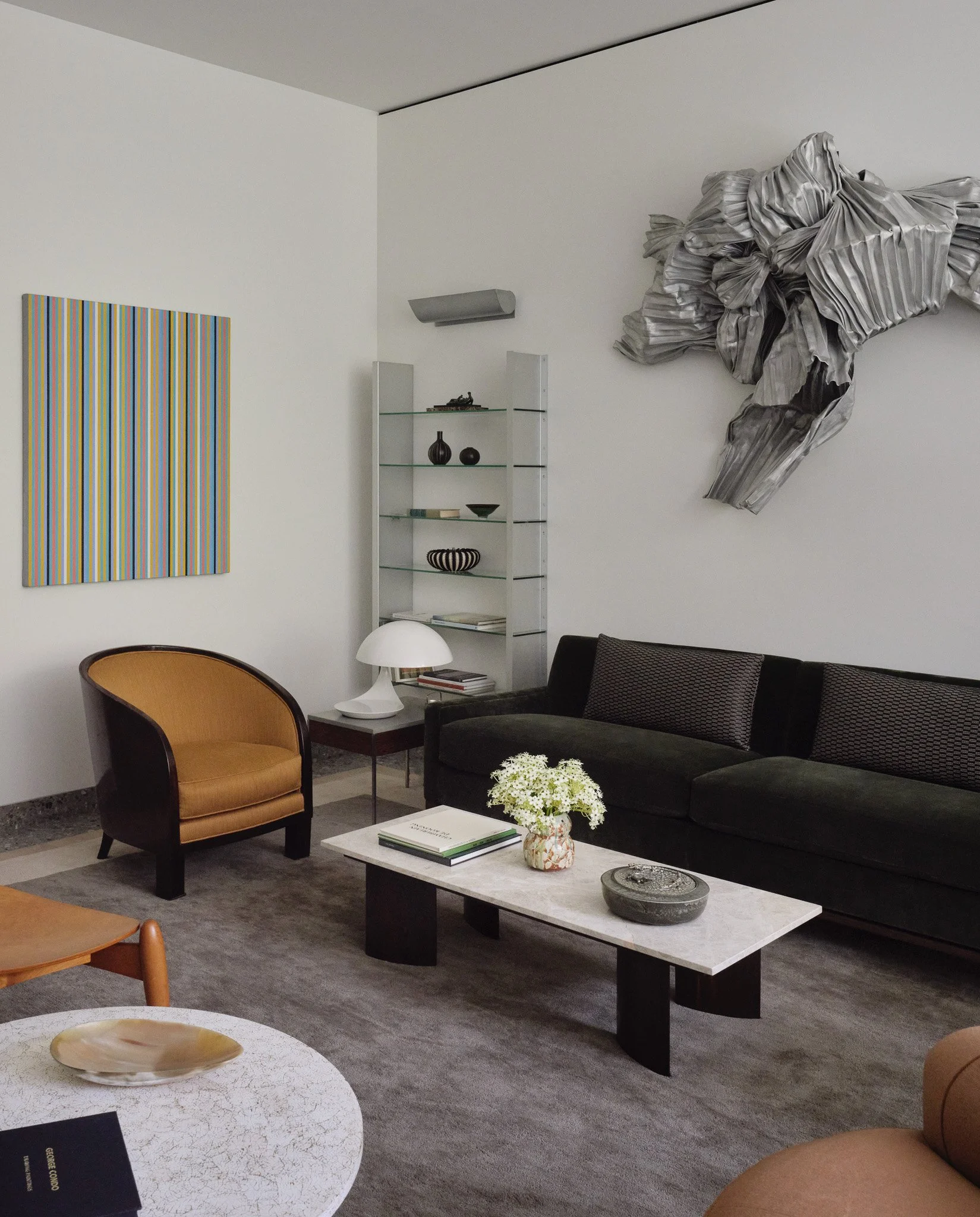 Sitting room with a metallic wall sculpture and glass shelving in a West Village townhouse by JG Neukomm Architecture