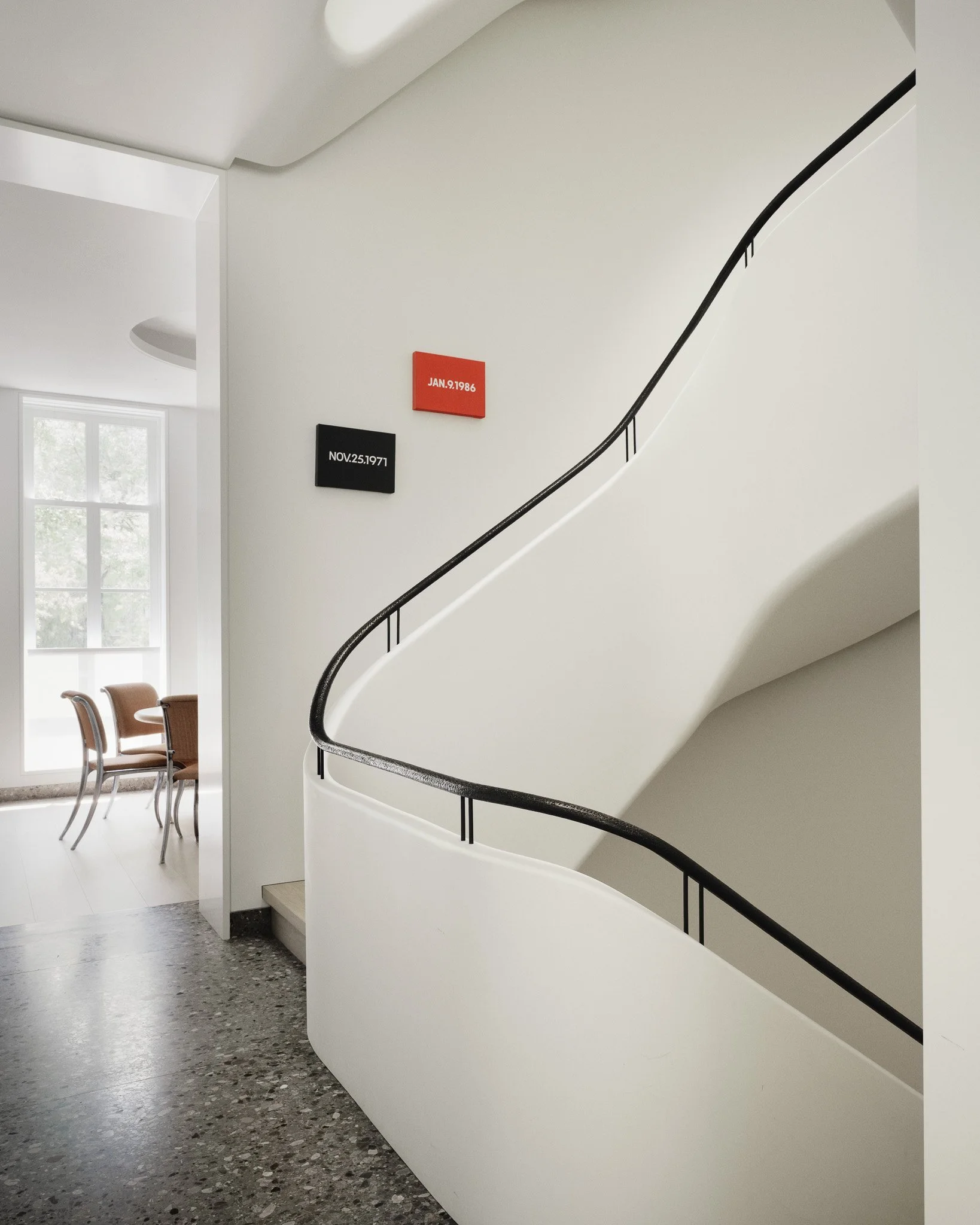 Sculptural white staircase with a curved black handrail in a West Village townhouse by JG Neukomm Architecture