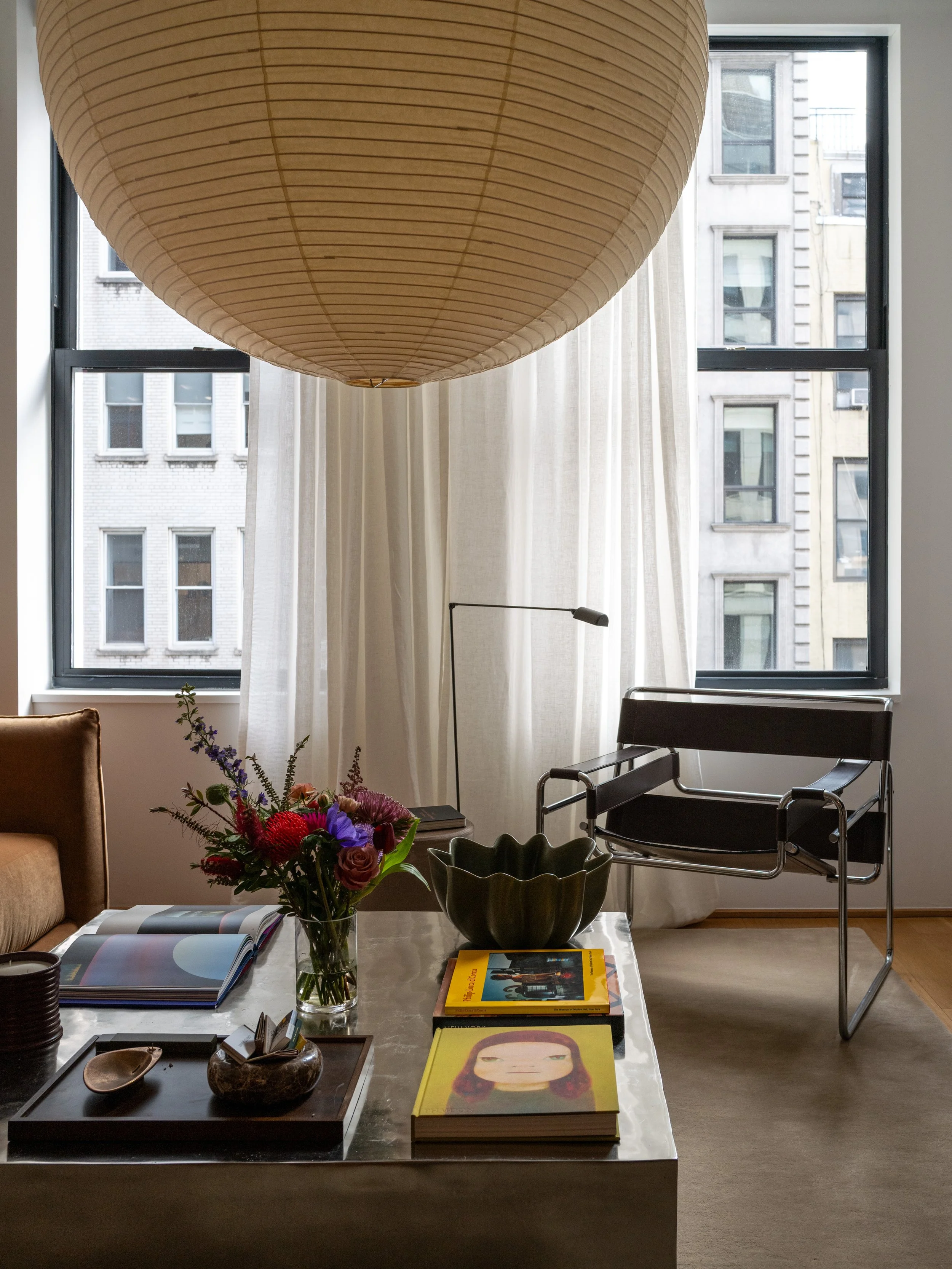 Seating area detail with chrome Wassily chair, concrete plinth coffee table, and sheer-curtained windows