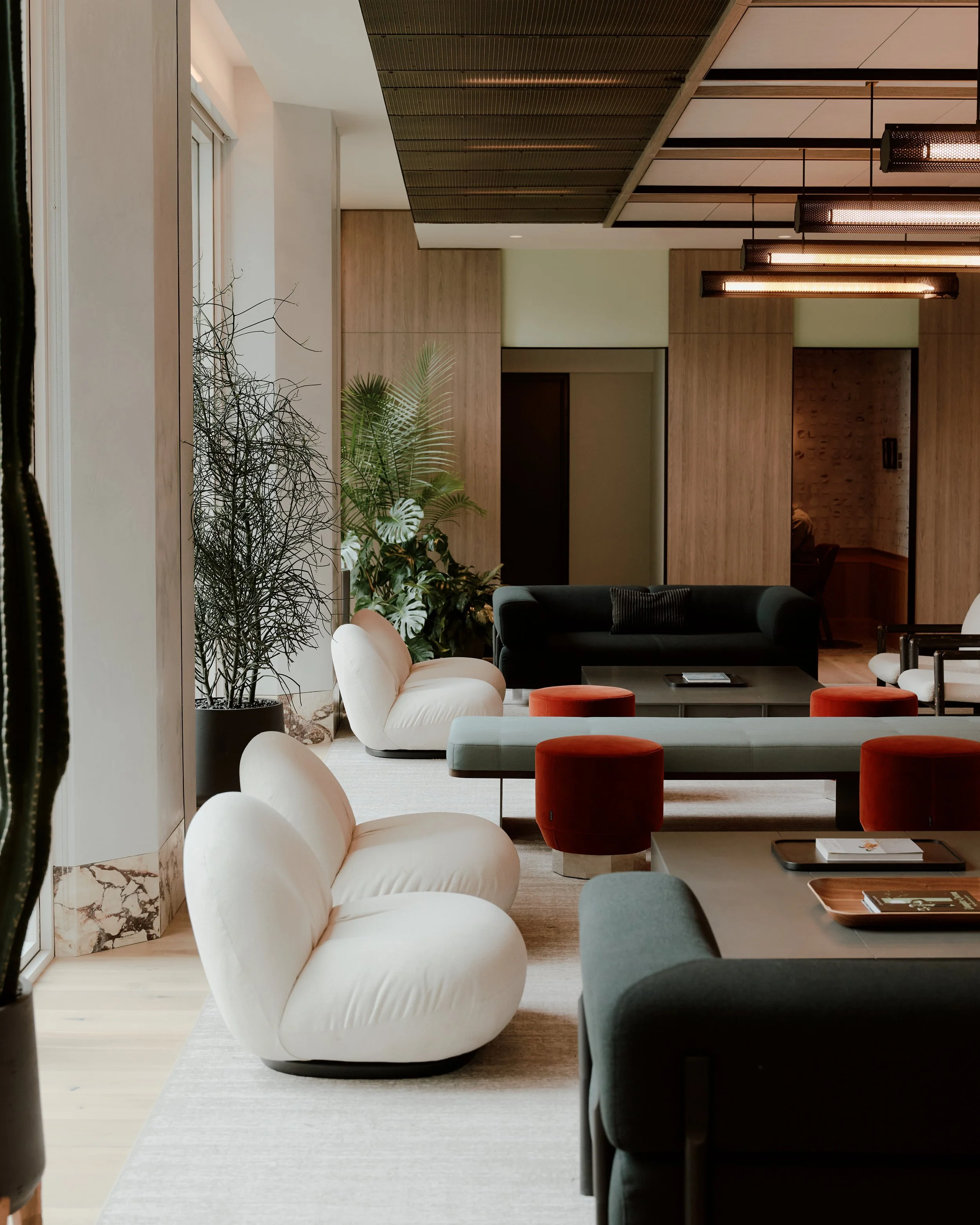 Residents lounge seating area with custom furnishings, floor-to-ceiling windows, and warm material finishes at The Suffolk, a Lower East Side residential building, interiors by JG Neukomm Architecture