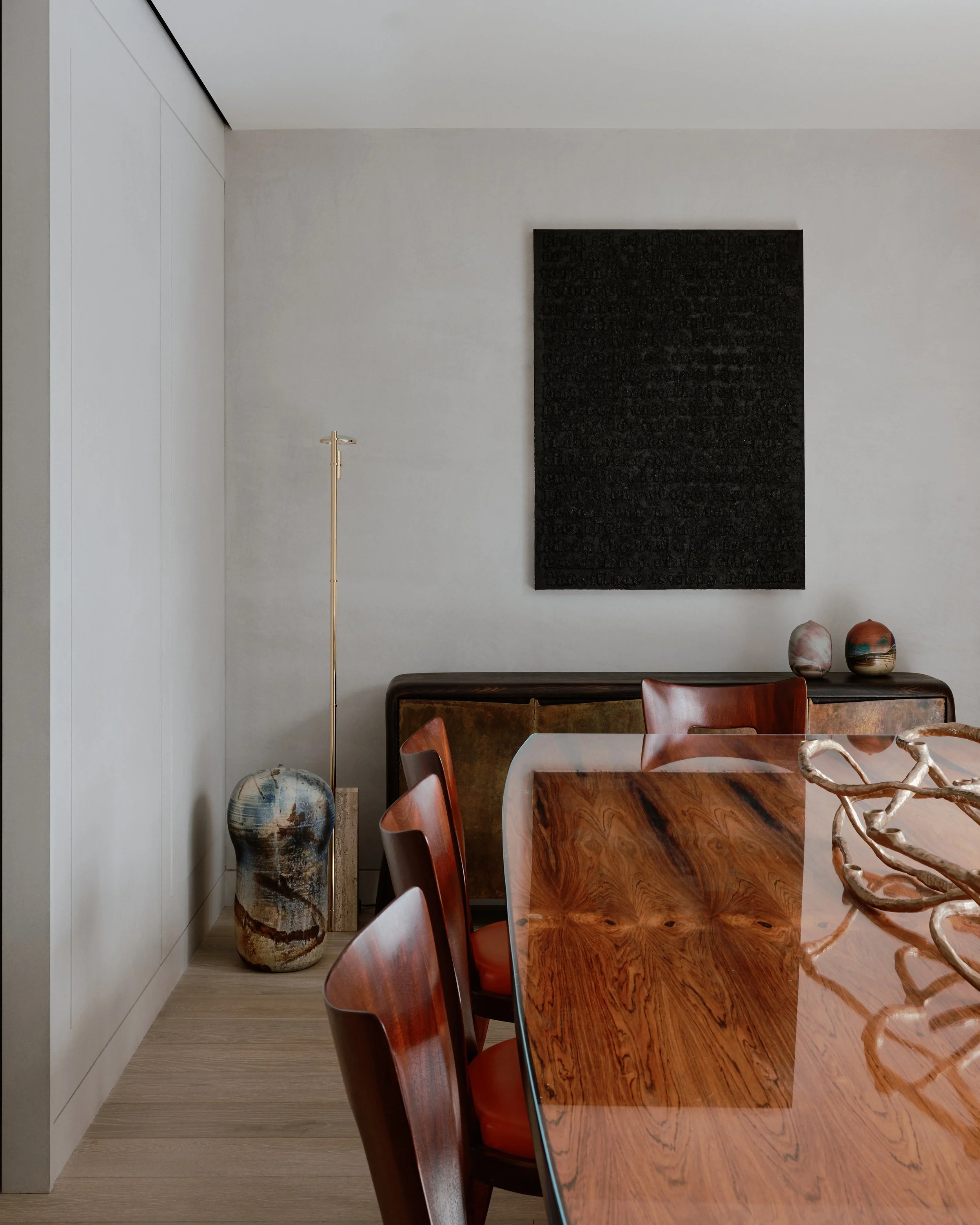 Dining room with a wood table and contemporary art in a West Village townhouse by JG Neukomm Architecture
