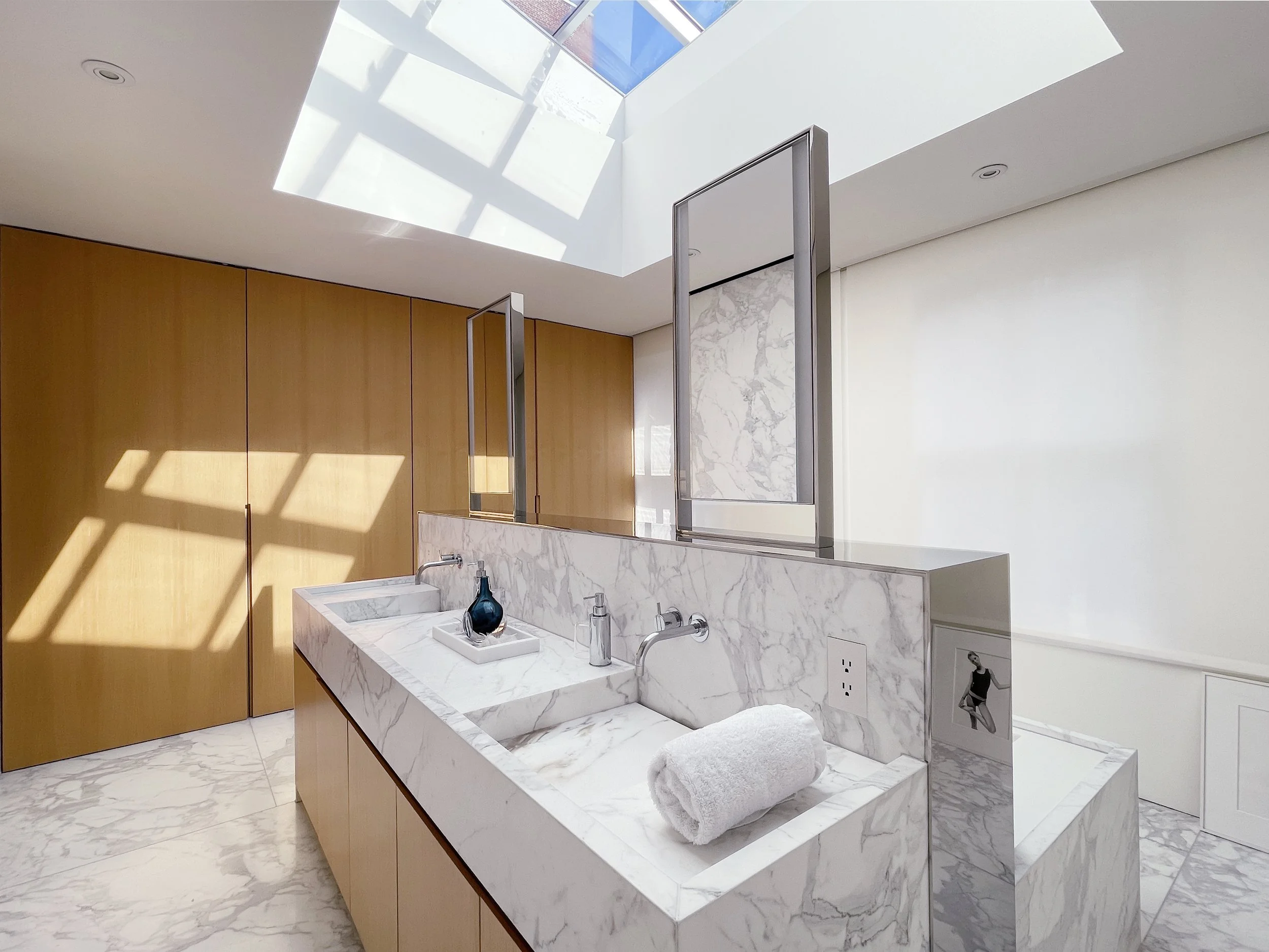 Carrara marble double vanity with integrated sinks and warm wood cabinetry in master bathroom of Fabien Baron's West Village townhouse by JG Neukomm Architecture