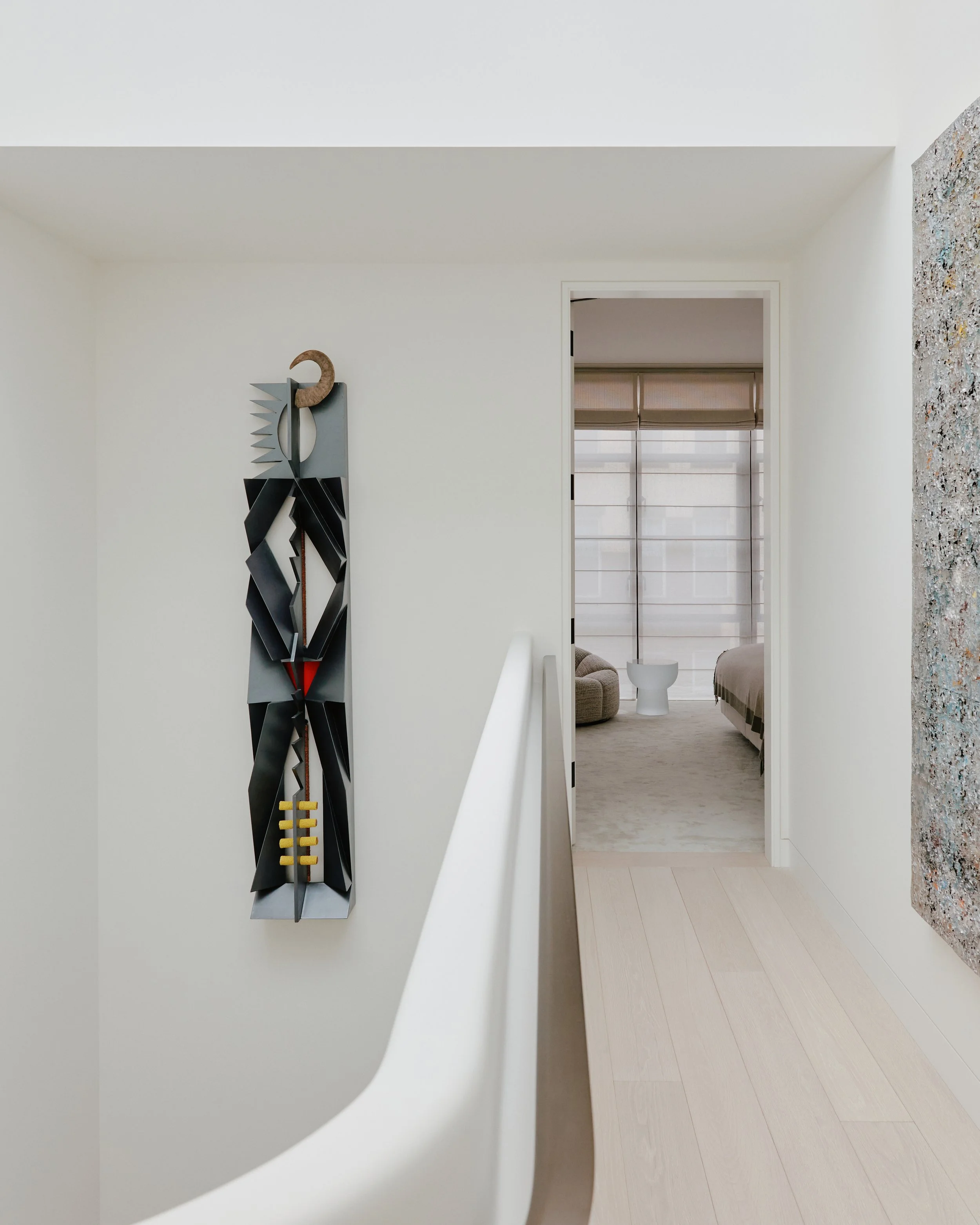 Upper hallway with a contemporary wall sculpture beside the sculptural staircase in a West Village townhouse by JG Neukomm Architecture