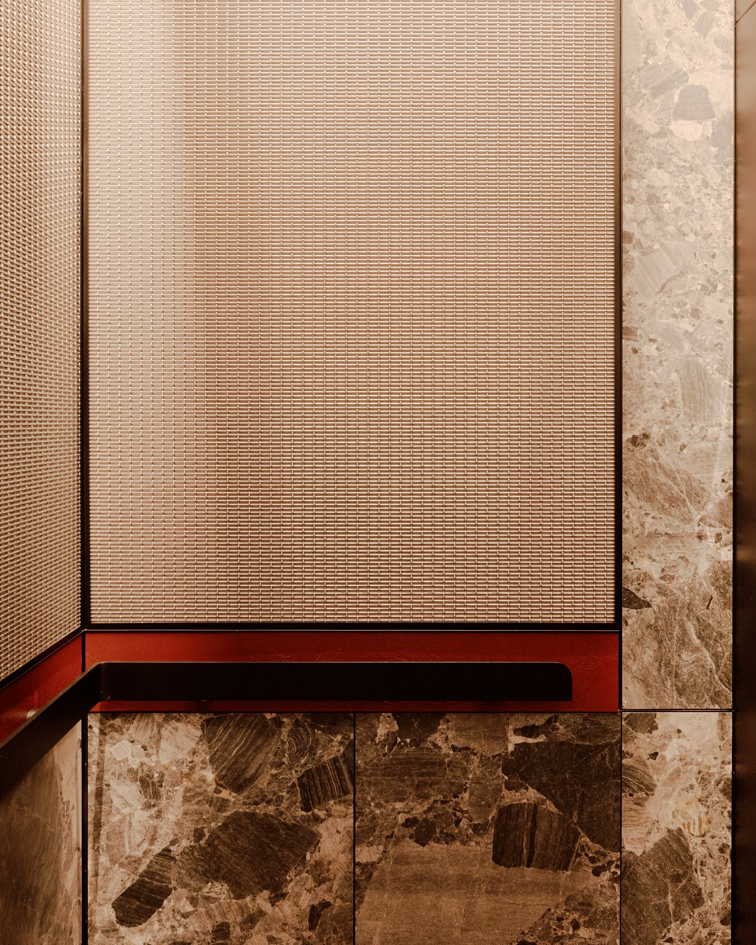 Material detail featuring decorative metal mesh, richly veined stone, and custom millwork at The Suffolk, a Lower East Side residential building, interiors by JG Neukomm Architecture