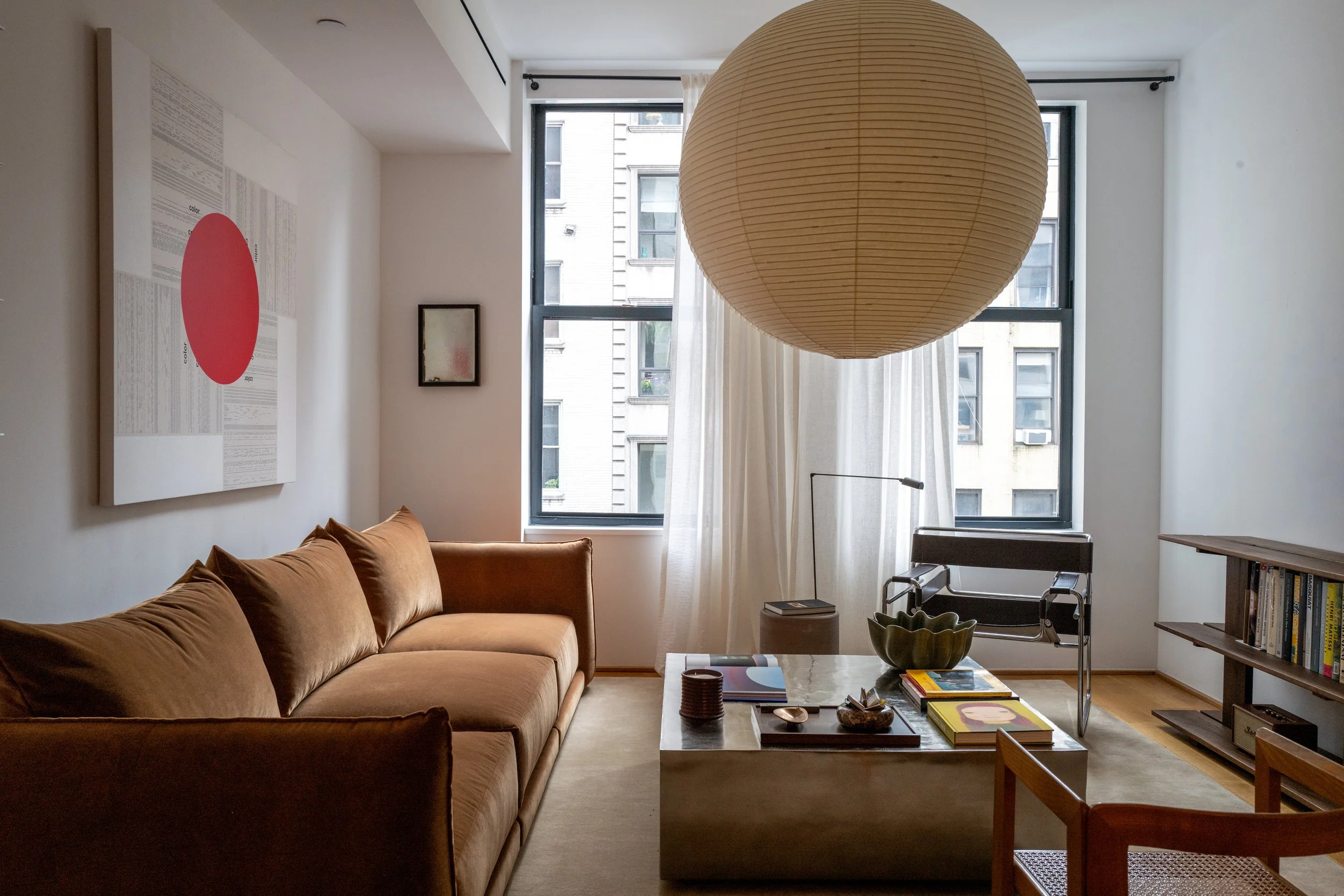 Full living room view with window wall, paper globe pendant, and low coffee table