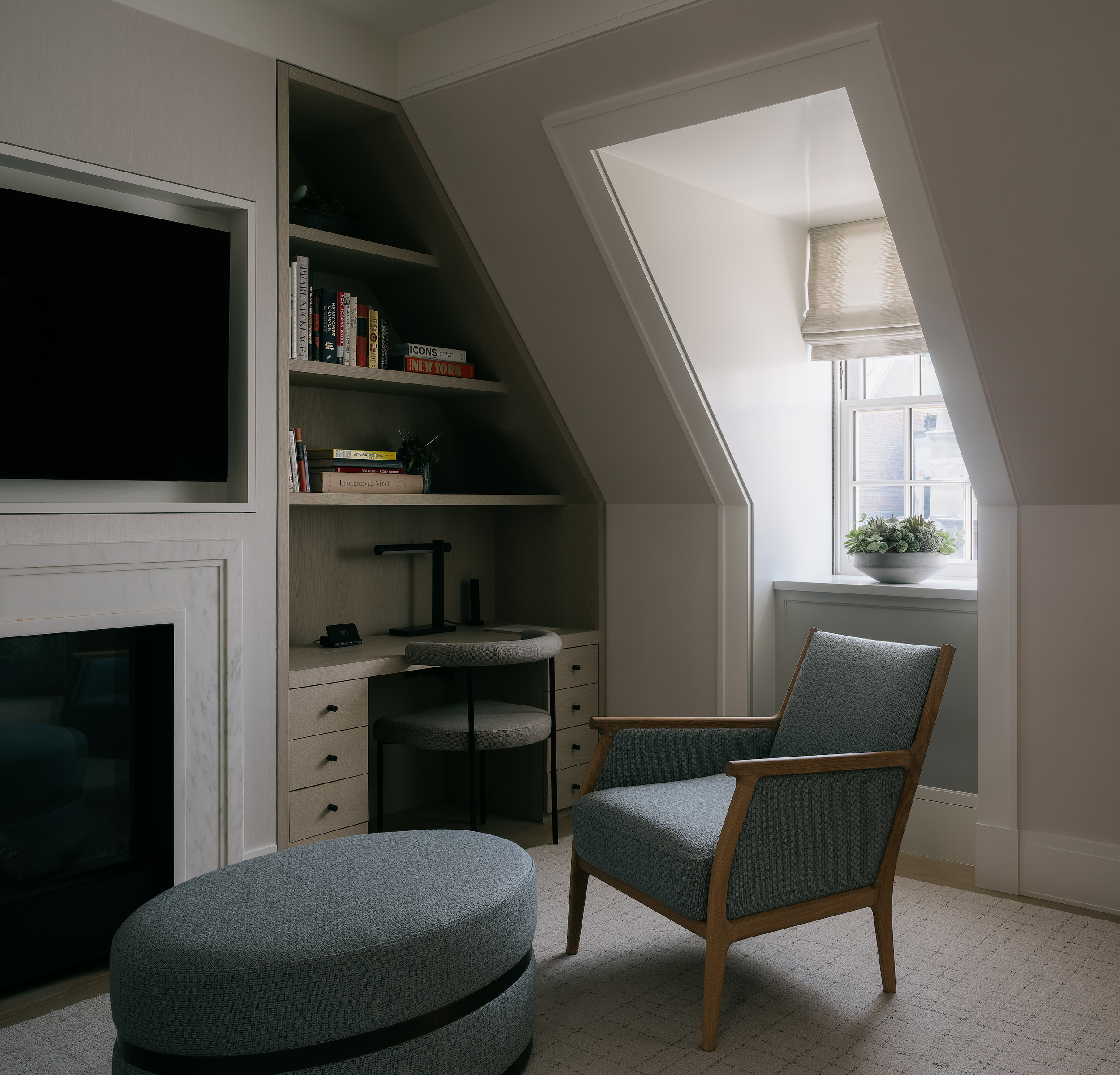 Top-floor study with a sloped dormer ceiling, built-in shelving, and a marble fireplace