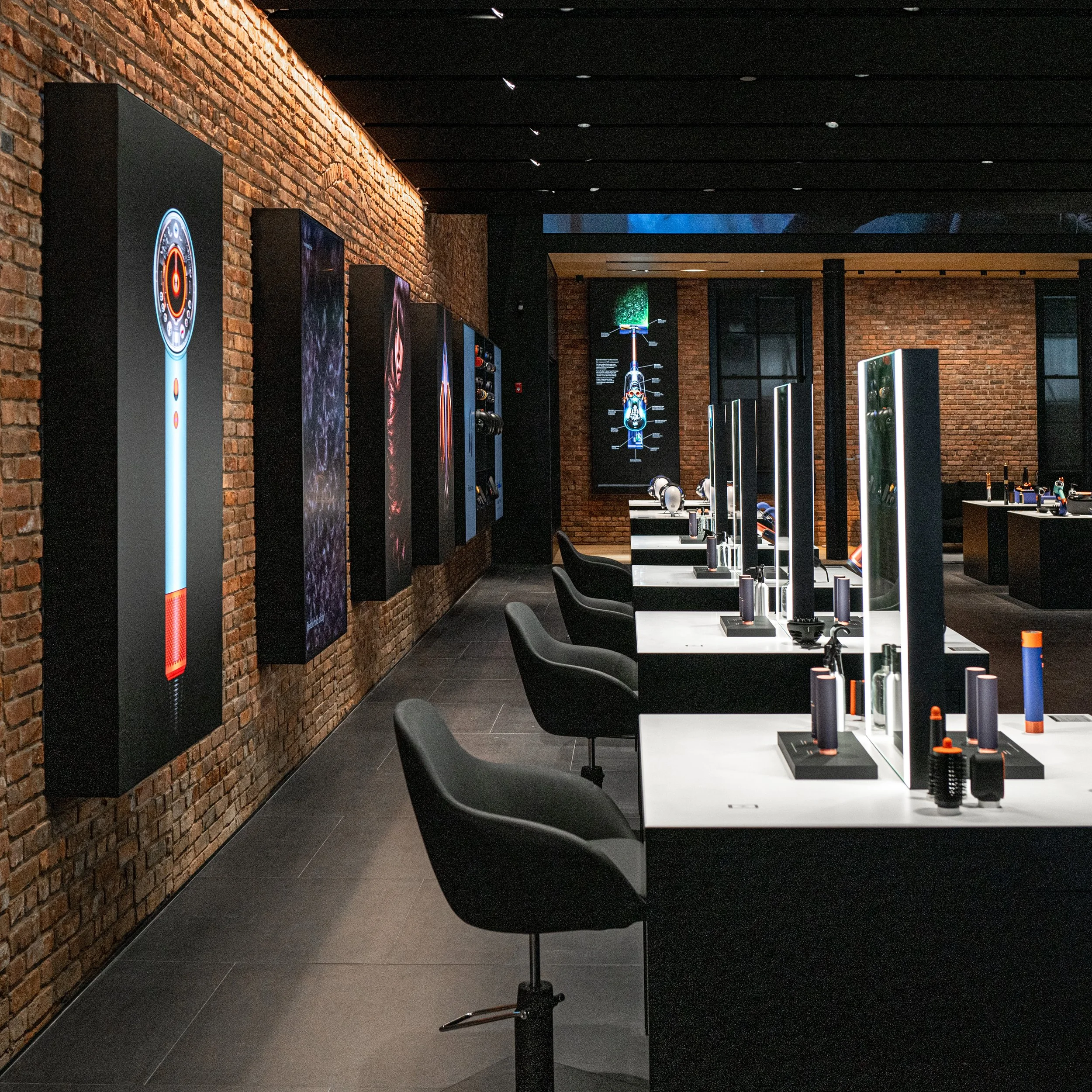 Dyson Demo Store styling stations with chairs and mirrors lining an exposed brick corridor