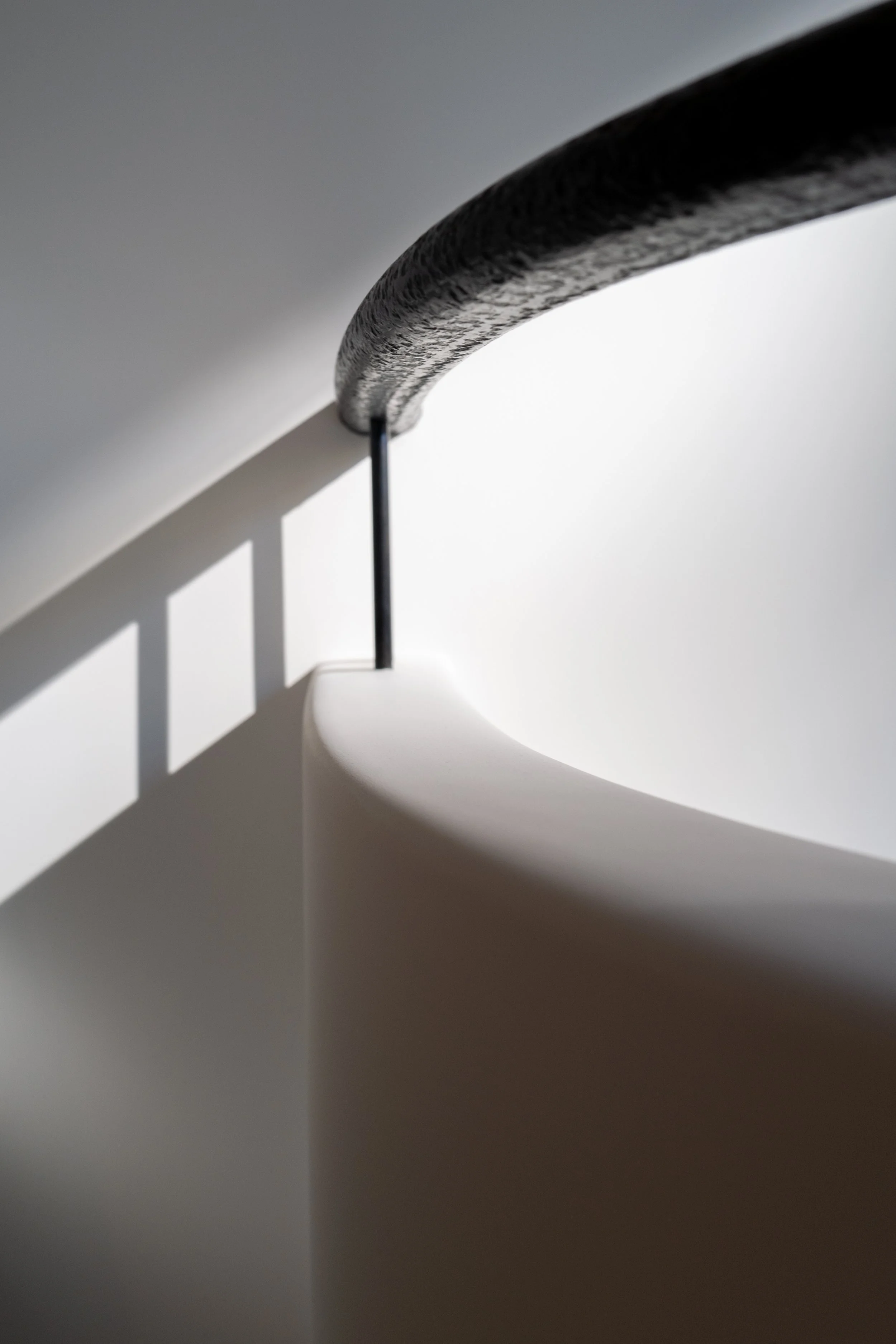 Curved leather-wrapped handrail over the sculptural staircase in a West Village townhouse by JG Neukomm Architecture