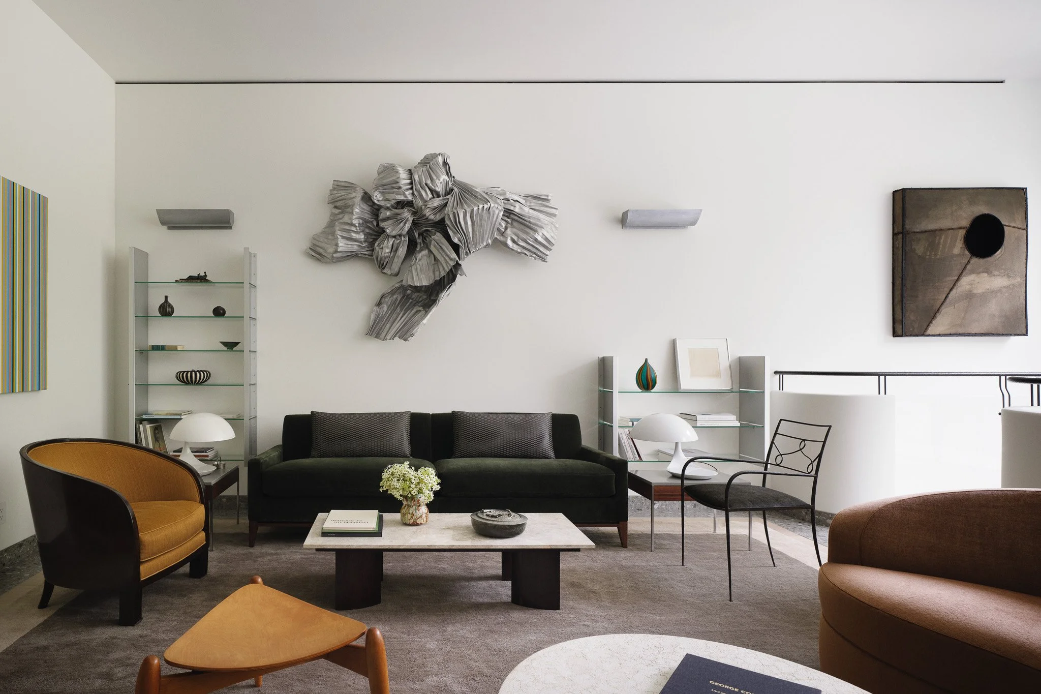 Sitting room with a metallic wall sculpture and glass shelving in a West Village townhouse by JG Neukomm Architecture
