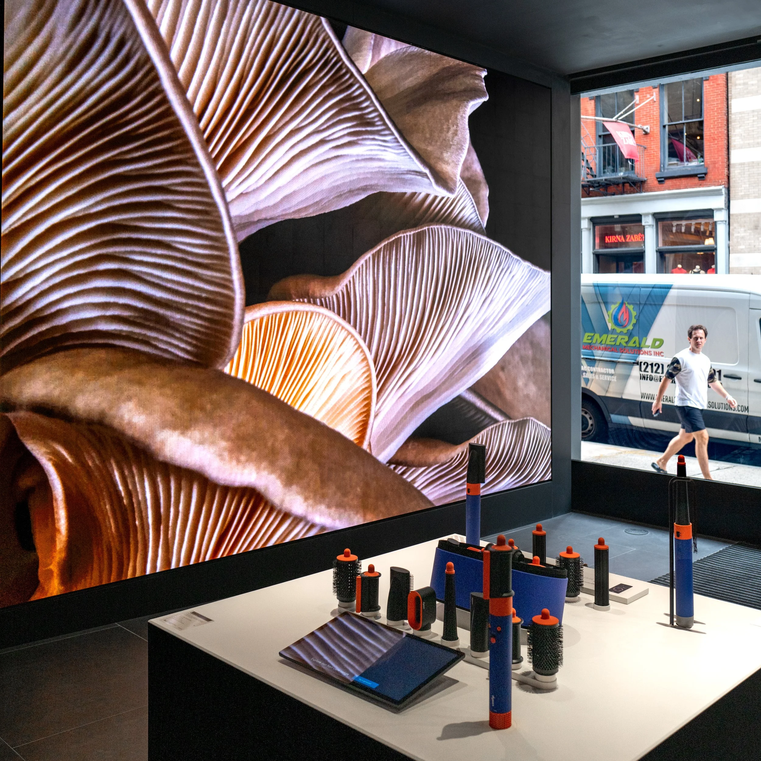 Dyson Demo Store hair styling counter with tools displayed below an oyster mushroom screen beside a street window
