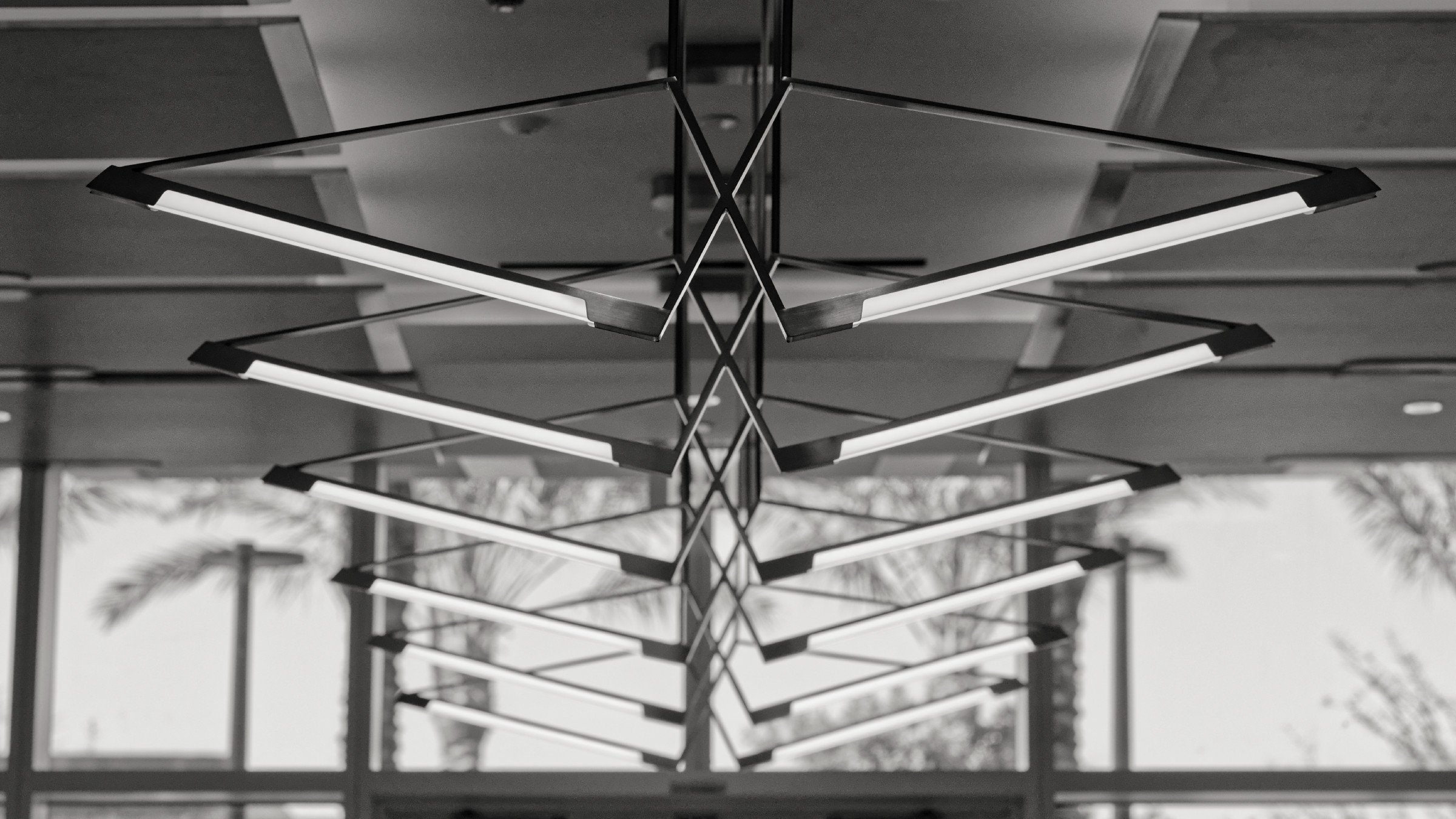 JGNA residential pavilion detail of a mirrored ceiling reflecting an angular linear light fixture and palms