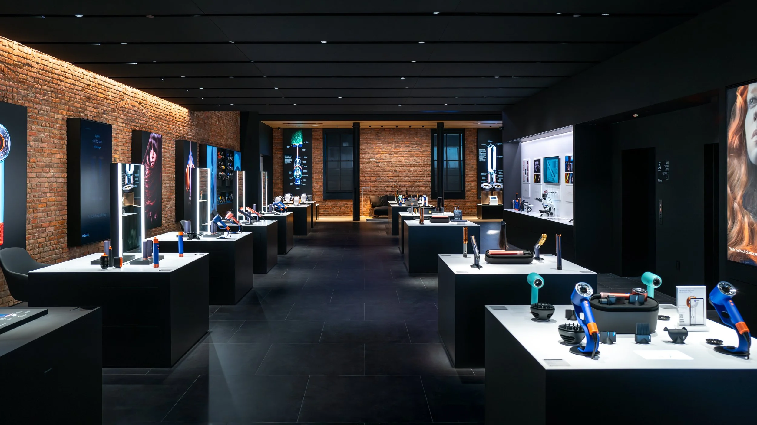 Wide view of the Dyson Demo Store with rows of black plinths displaying hair dryers against brick walls, designed by JGNA