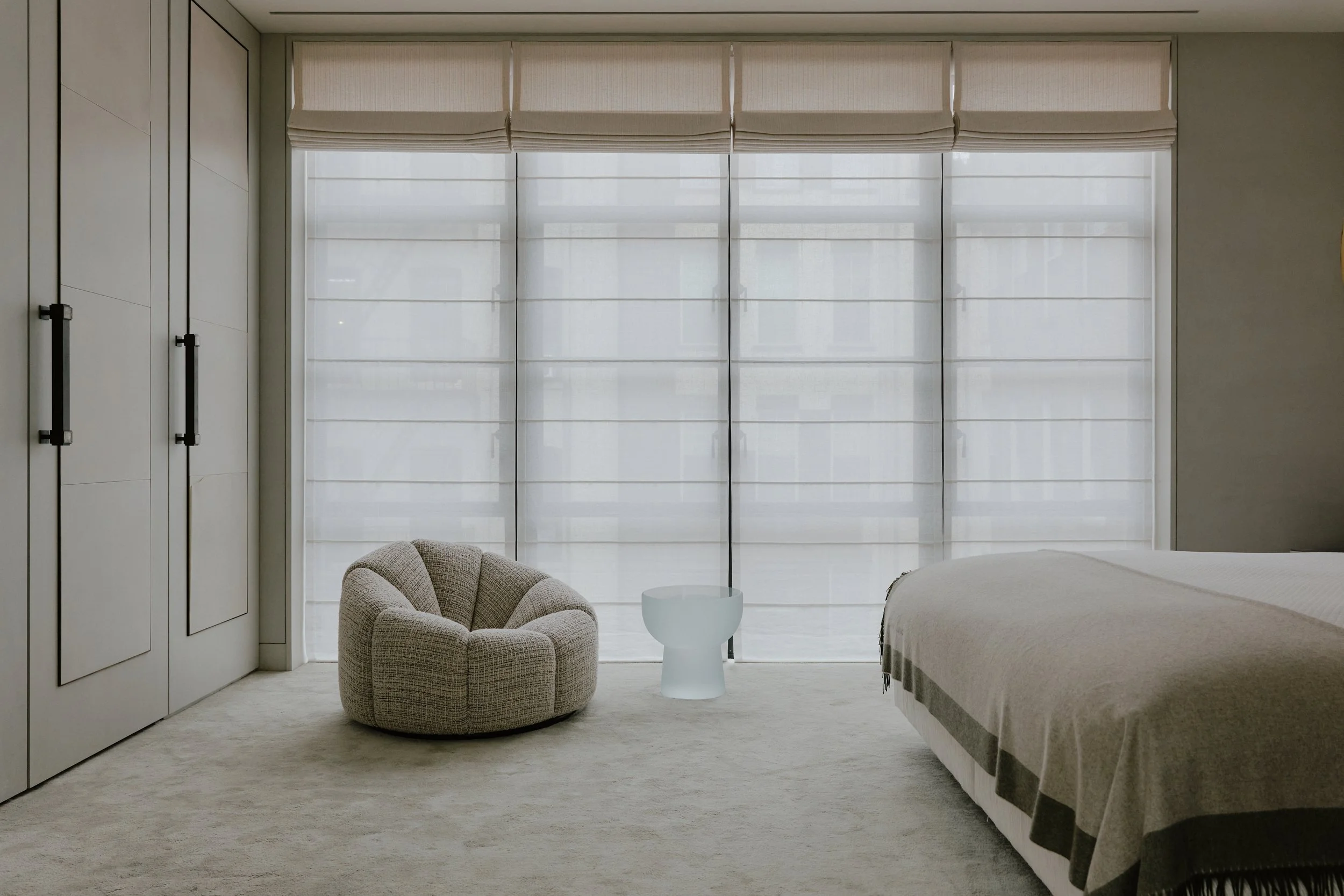 Bedroom with a boucle lounge chair and floor-to-ceiling windows in a West Village townhouse by JG Neukomm Architecture