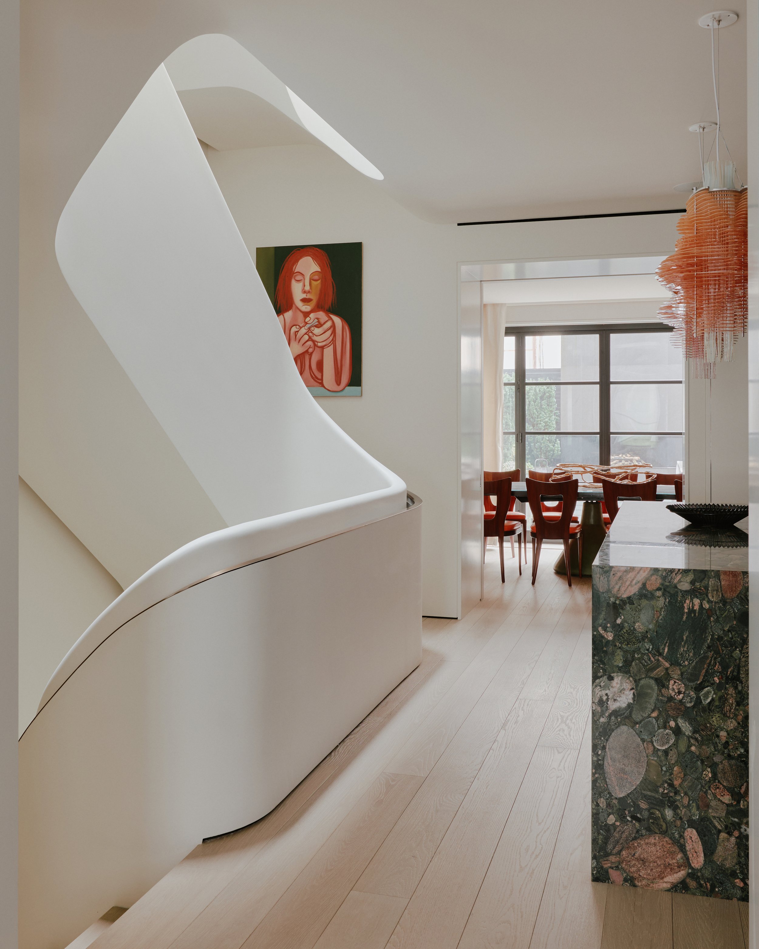 Sculptural white plaster staircase framing the dining area beyond in a West Village townhouse by JG Neukomm Architecture