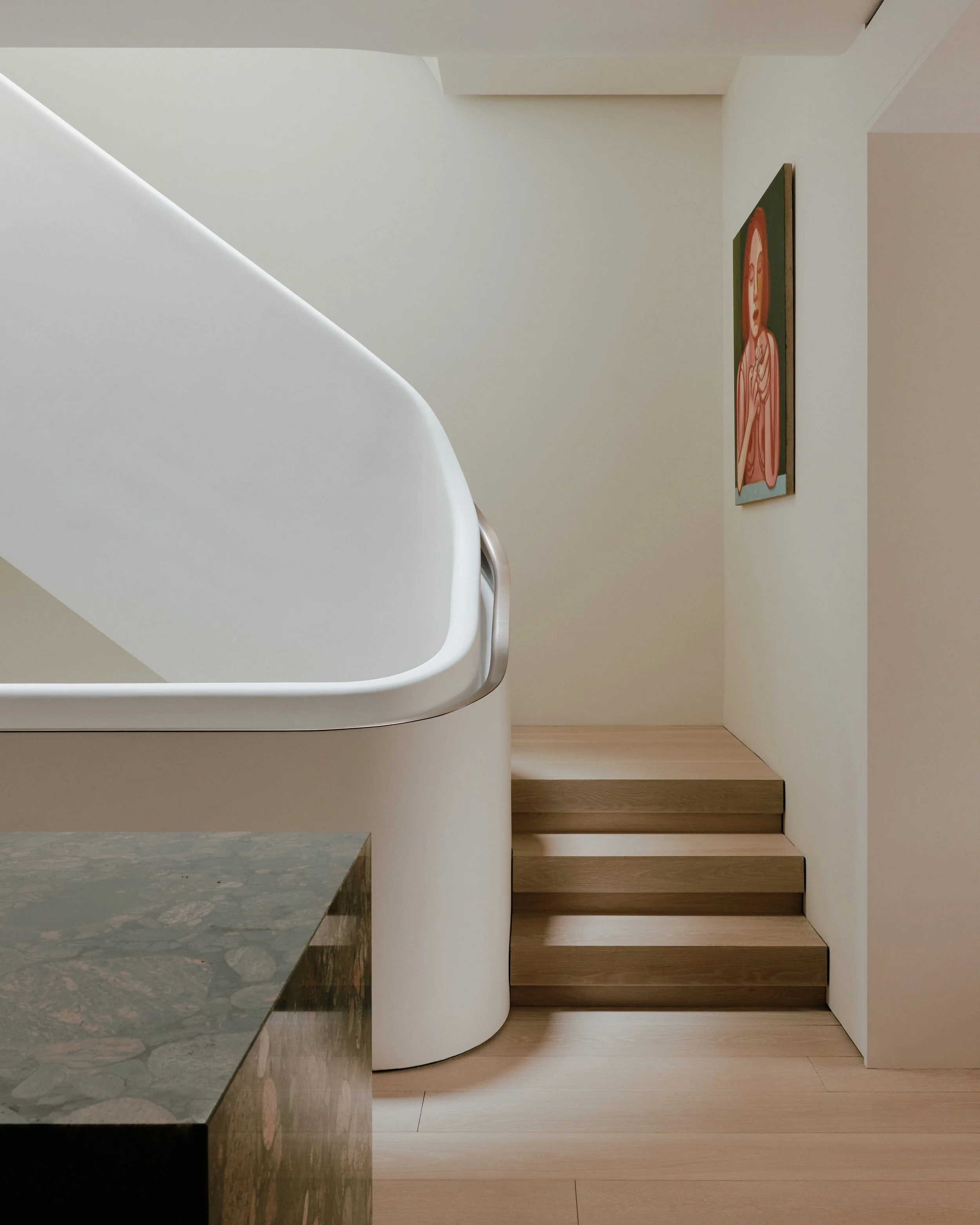 Base of the sculptural white plaster staircase meeting oak treads in a West Village townhouse by JG Neukomm Architecture