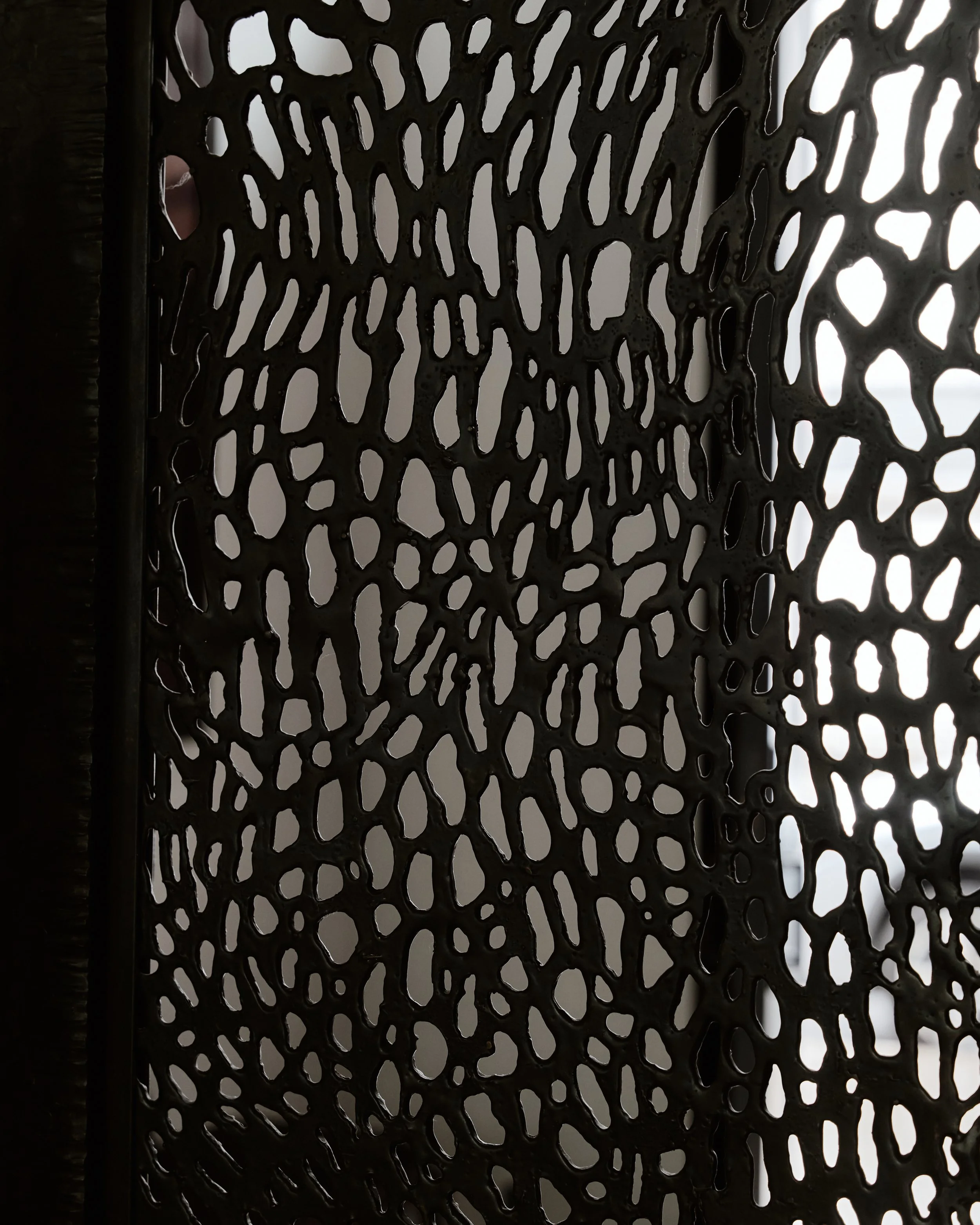 Detail of a custom perforated-metal screen with an organic cut-out pattern in a West Village townhouse by JG Neukomm Architecture