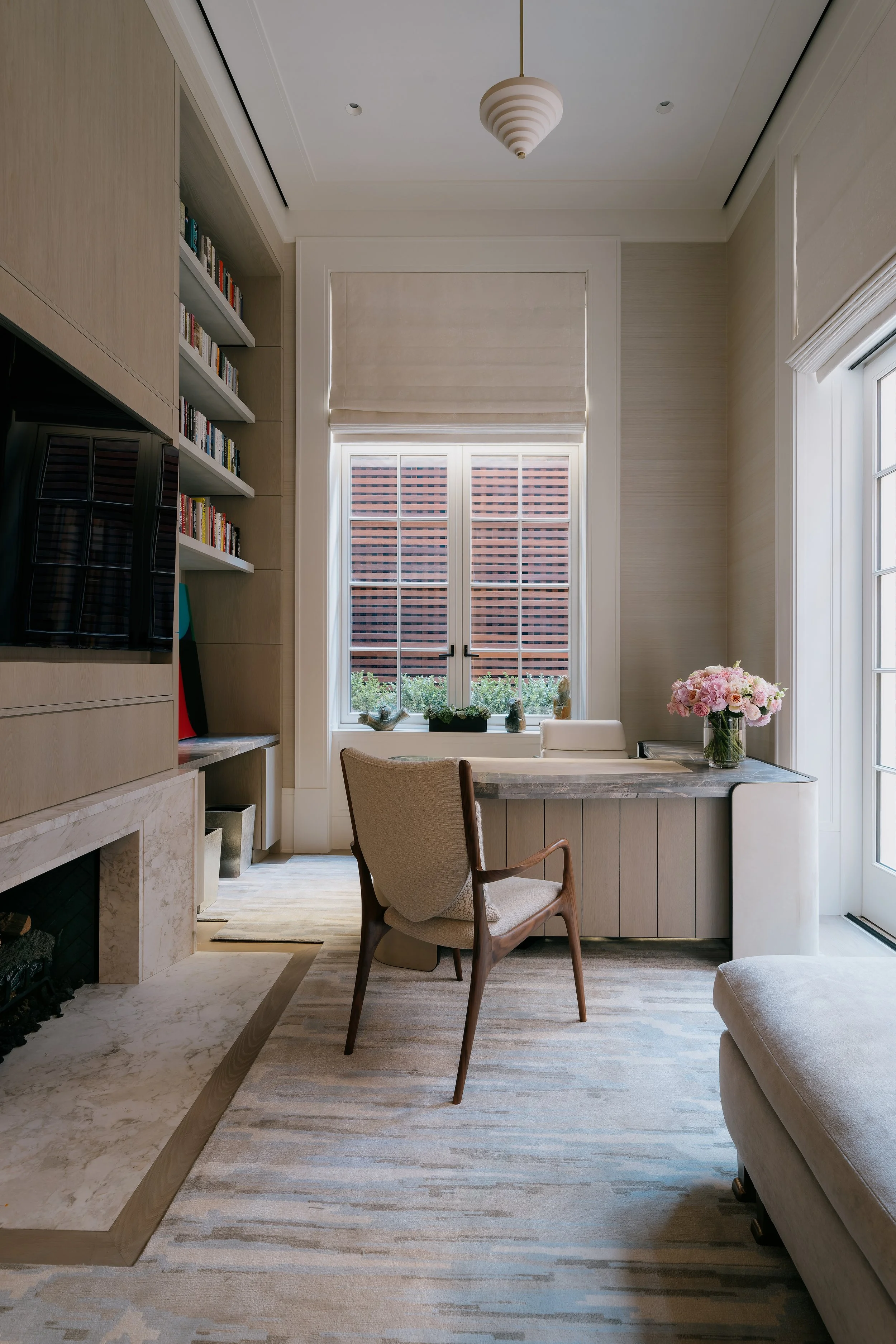 Home study with built-in bookshelves, a marble fireplace, and a mid-century desk chair
