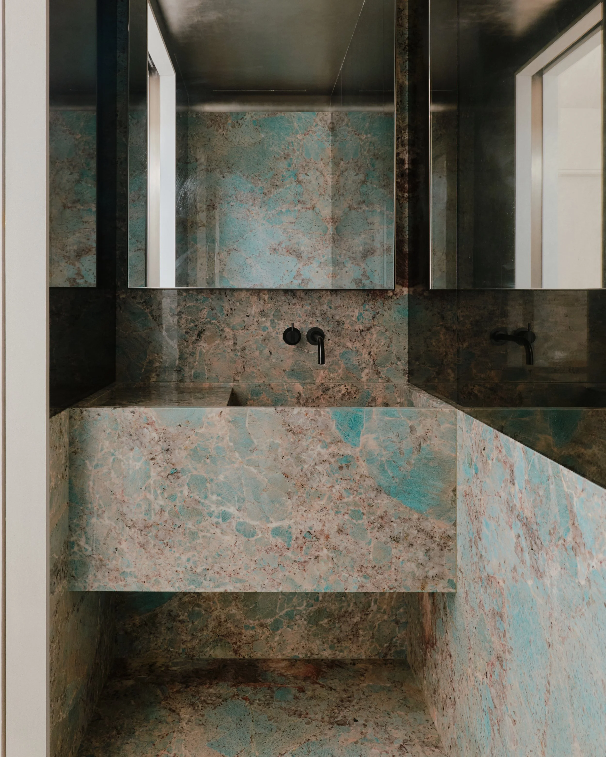 Bathroom clad in turquoise patinated stone with an integrated sink in a West Village townhouse by JG Neukomm Architecture