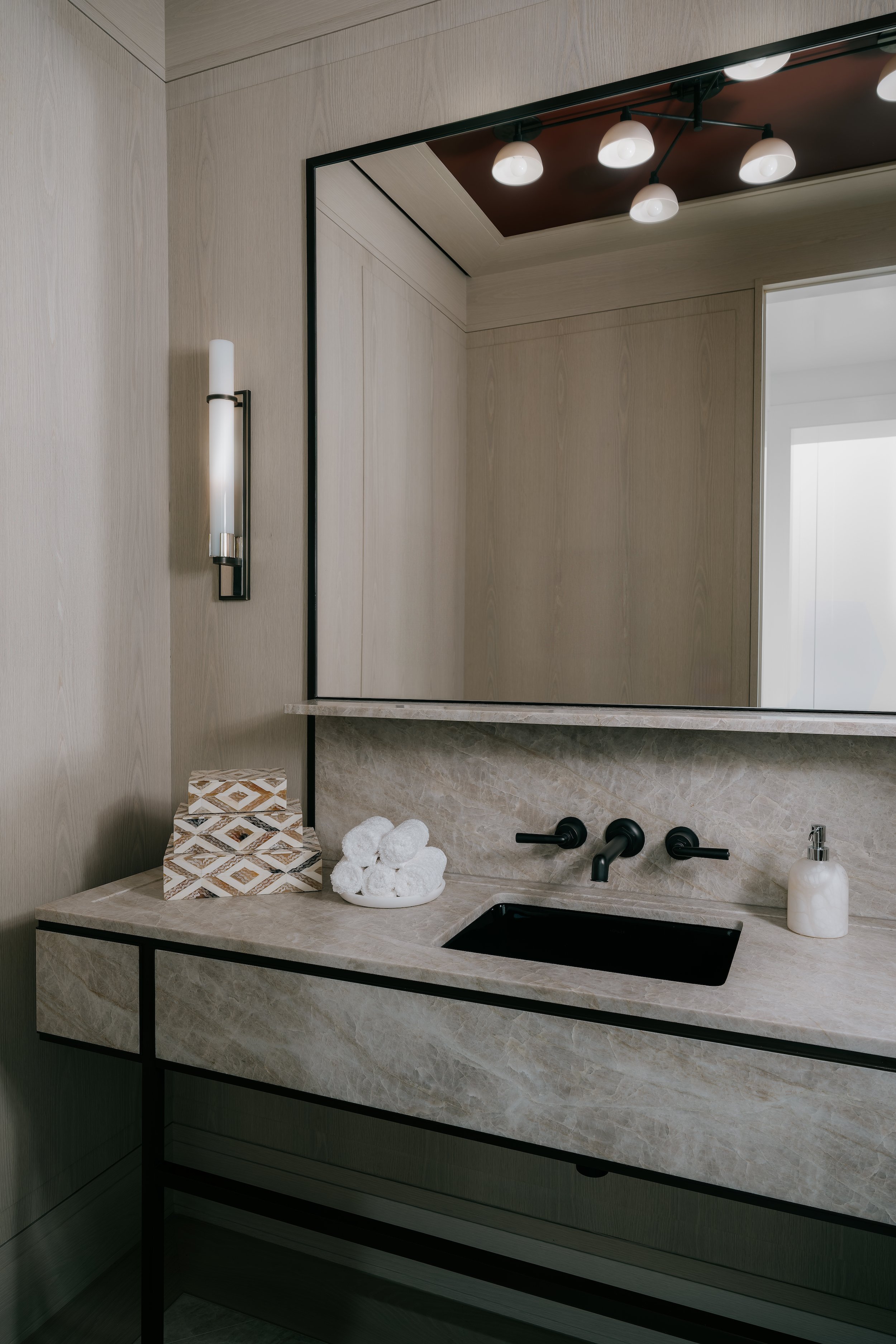 Bathroom vanity with a stone countertop, black wall-mounted faucet, and large backlit mirror