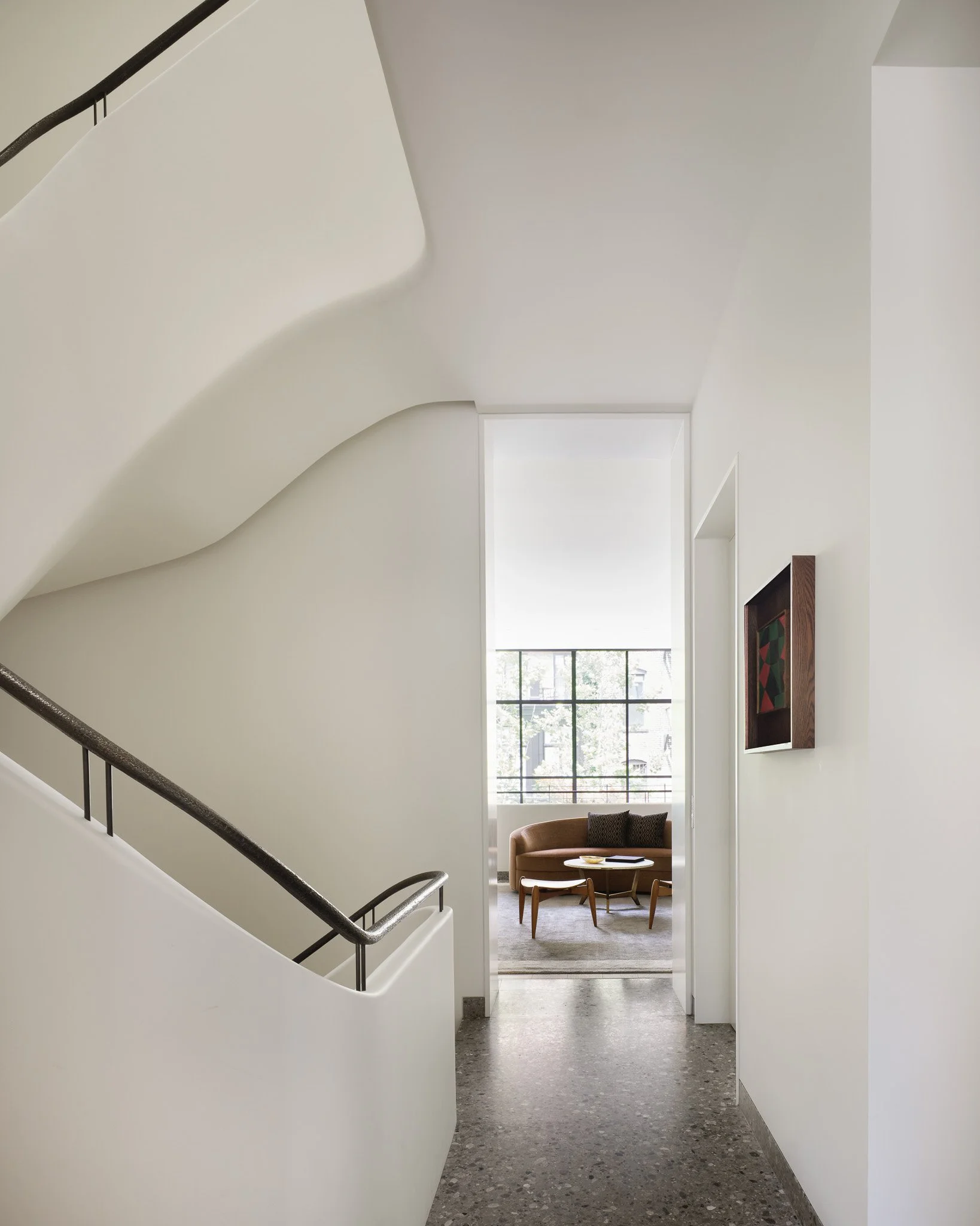 Stair landing with terrazzo flooring opening to a sitting room in a West Village townhouse by JG Neukomm Architecture