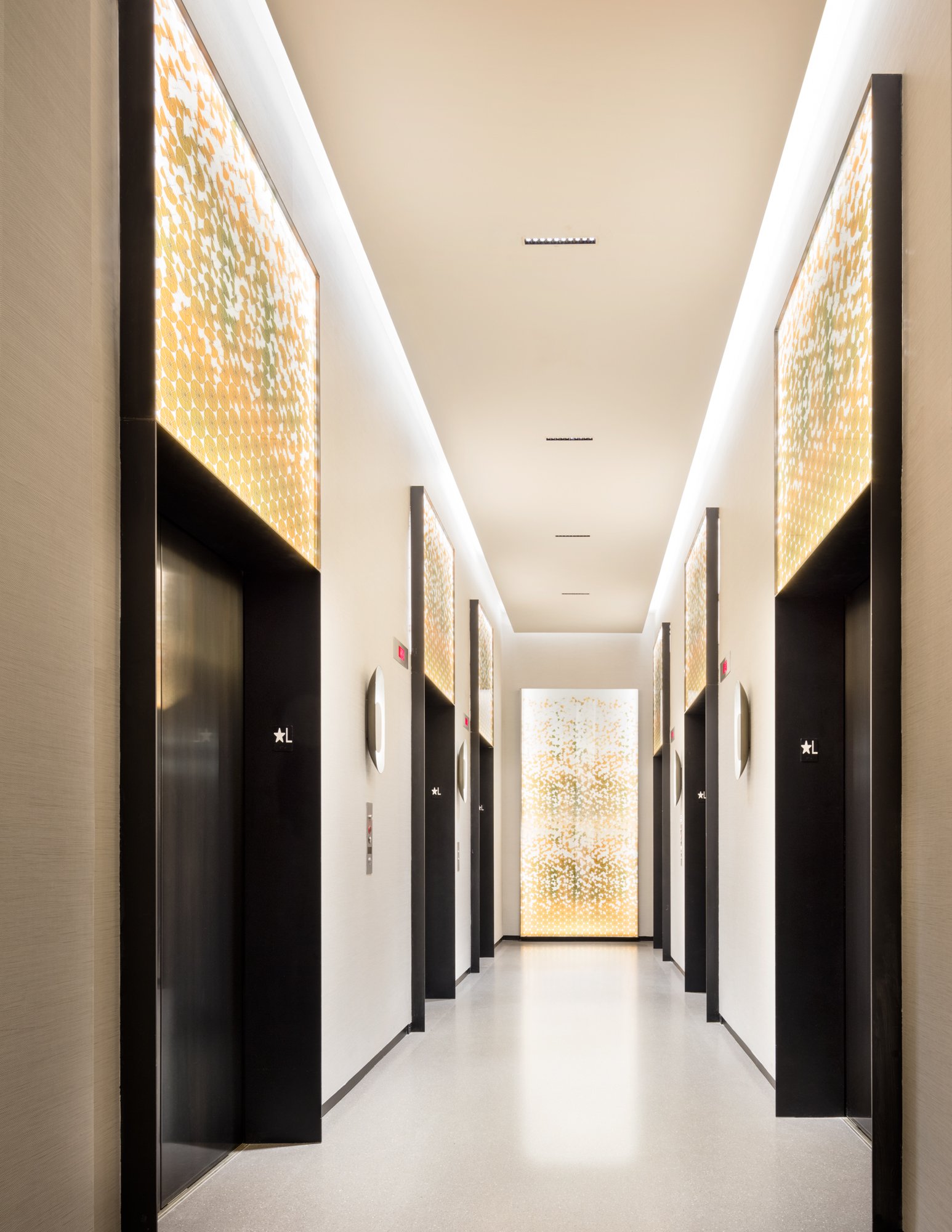 JGNA residential corridor lined with backlit patterned panels and concealed cove lighting